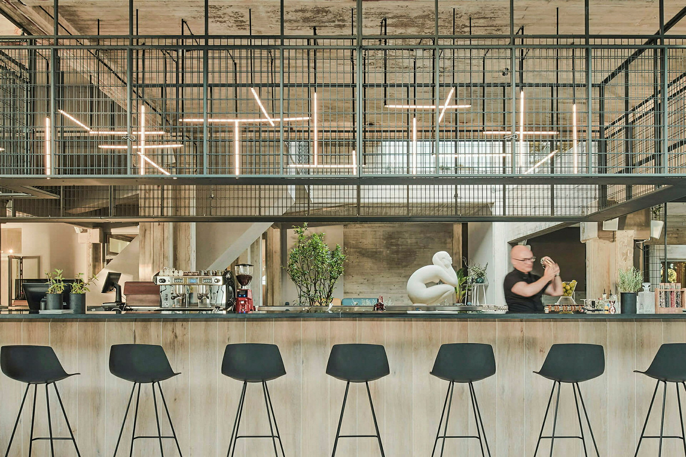 En modern bar med höga svarta stolar och industriell inredning. (AI-genererad text)