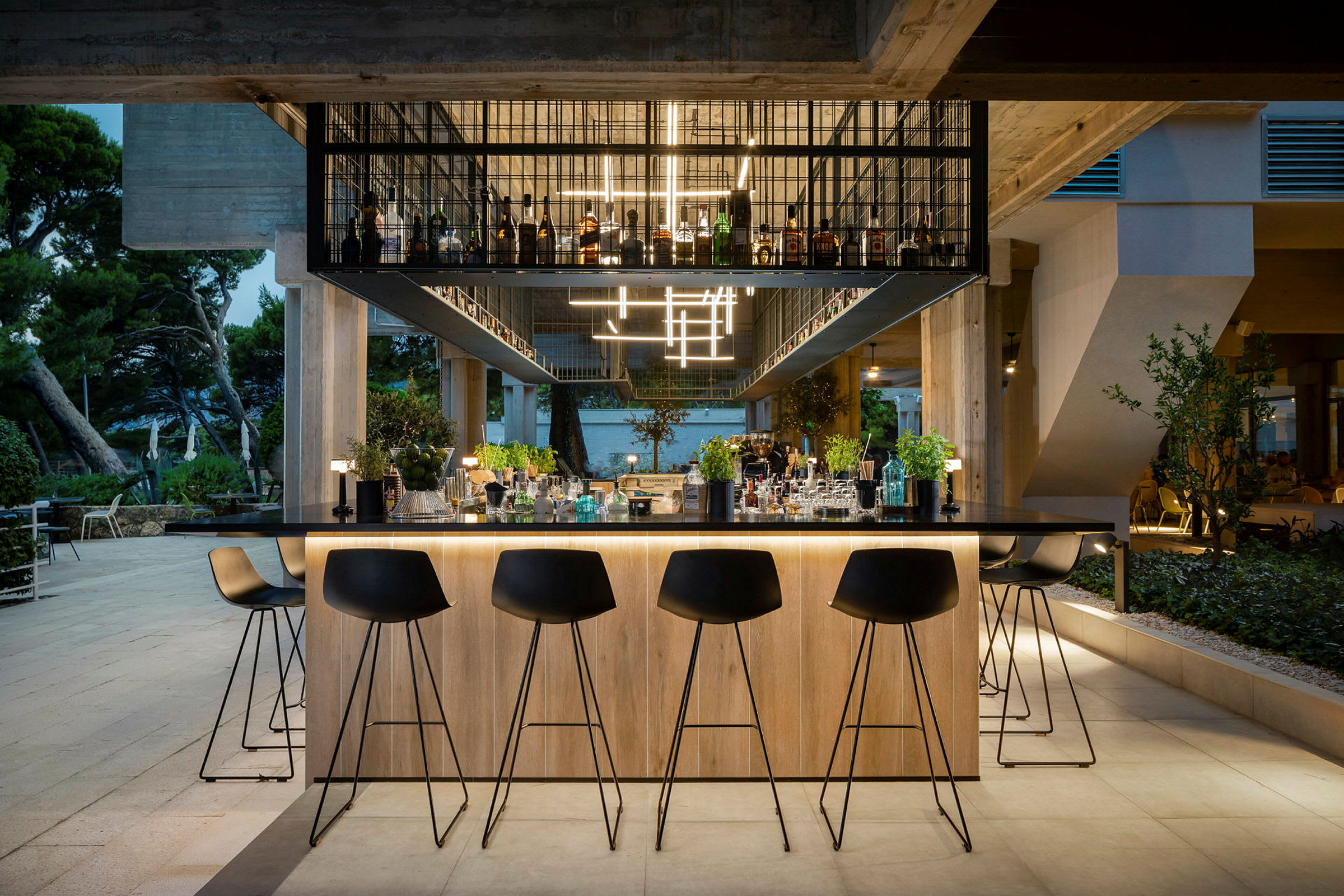 En väl upplyst bar med svarta barstolar och en hylla med flaskor ovanför, omgiven av en elegant miljö. (AI-genererad text)