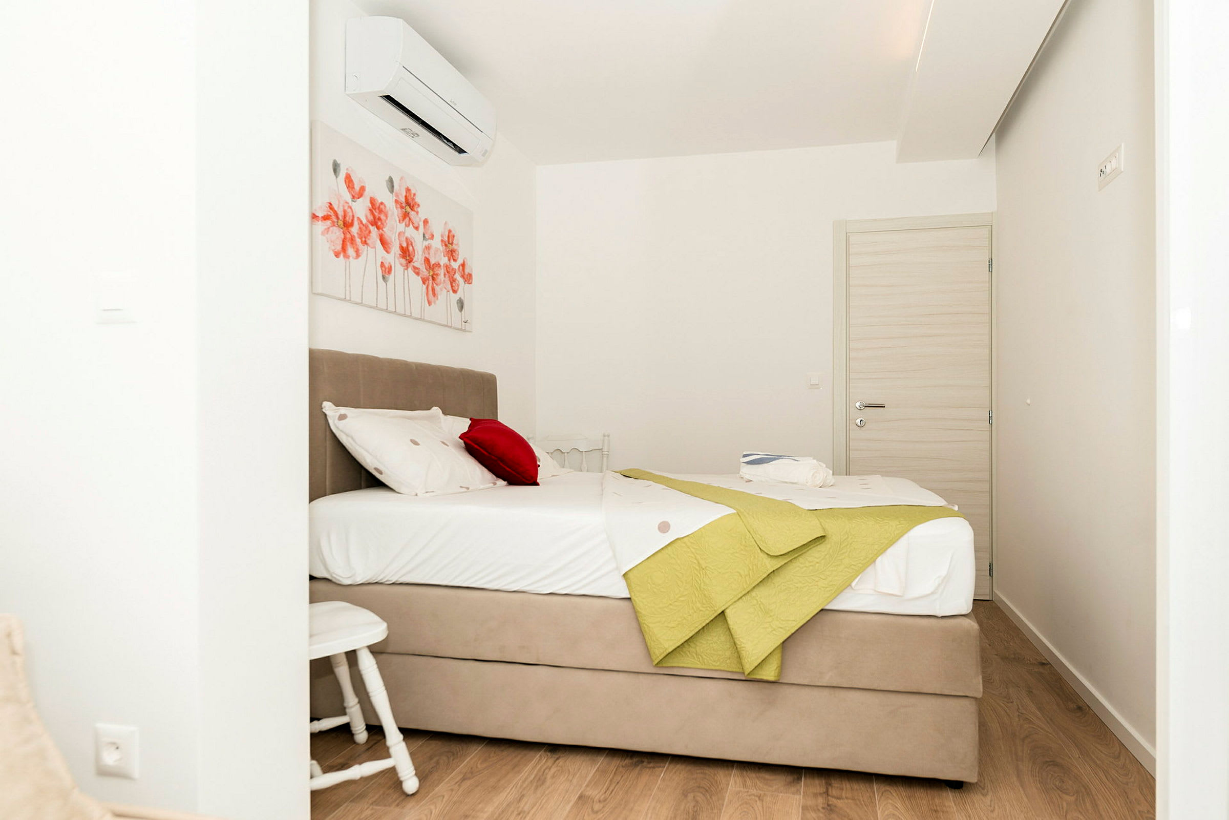 Ett hotellrum med en uppsatt säng, röda blommiga väggdekorationer och ljusa möbler. (AI-genererad text)