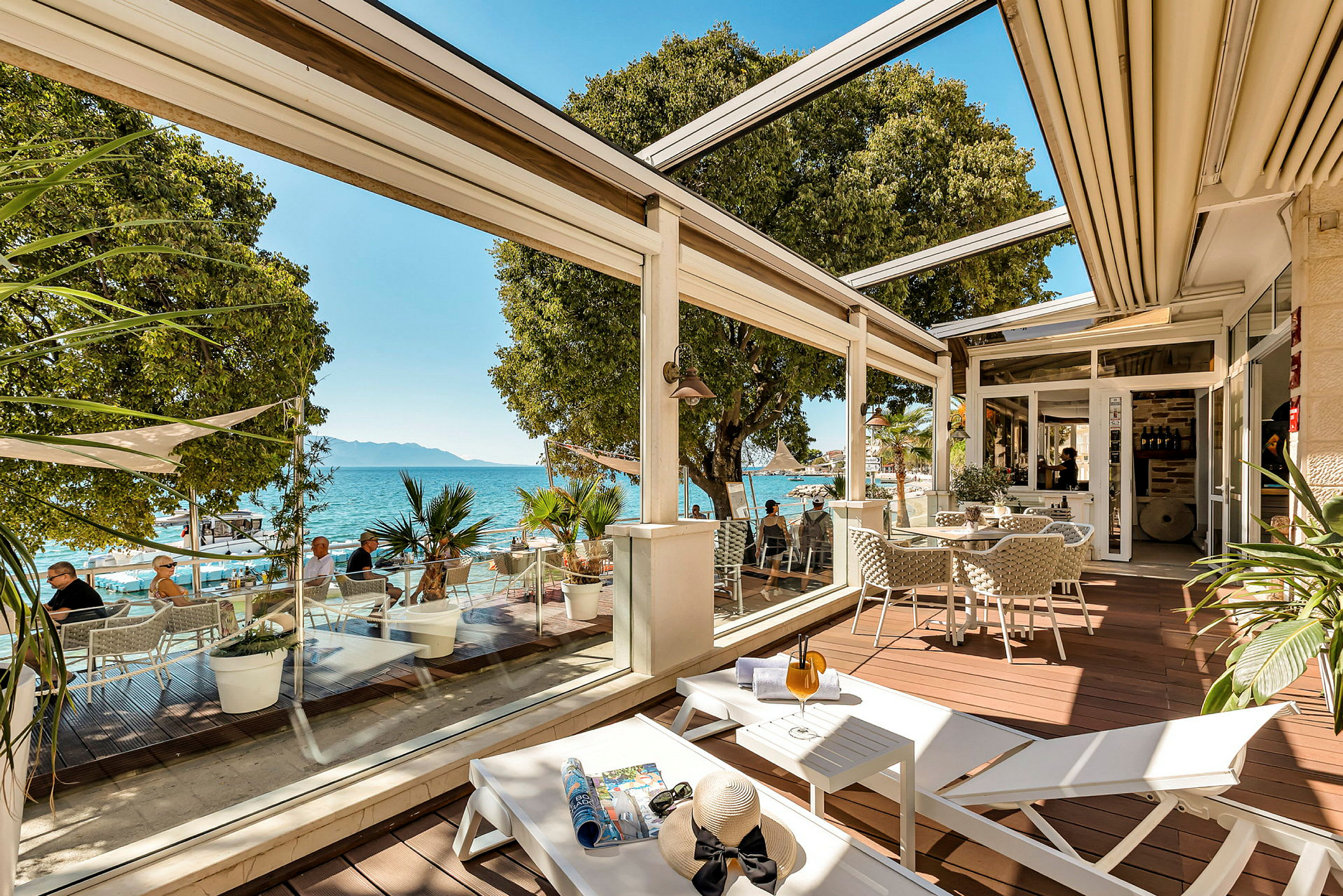 En terrass med sittplatser, solstolar och utsikt över havet. (AI-genererad text)