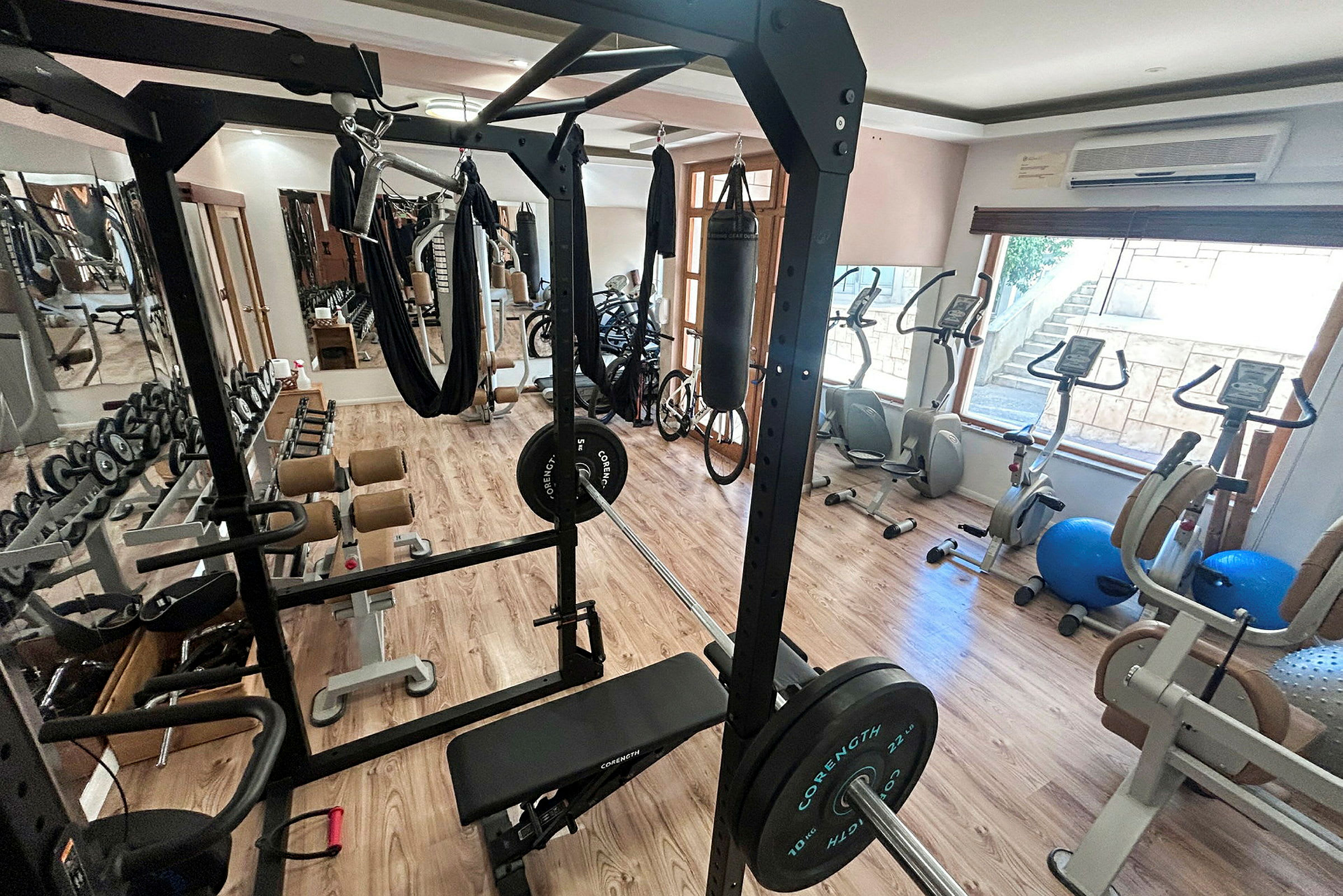 Bild av ett gym med träningsutrustning, såsom ett power rack, vikter och motionscyklar. (AI-genererad text)