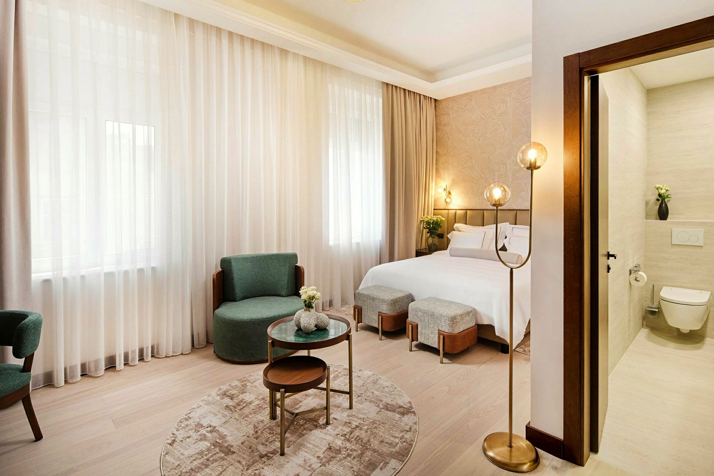 Ett modernt hotellrum med en dubbelsäng, stolar, soffbord och en delvis synlig badrumsdel. (AI-genererad text)