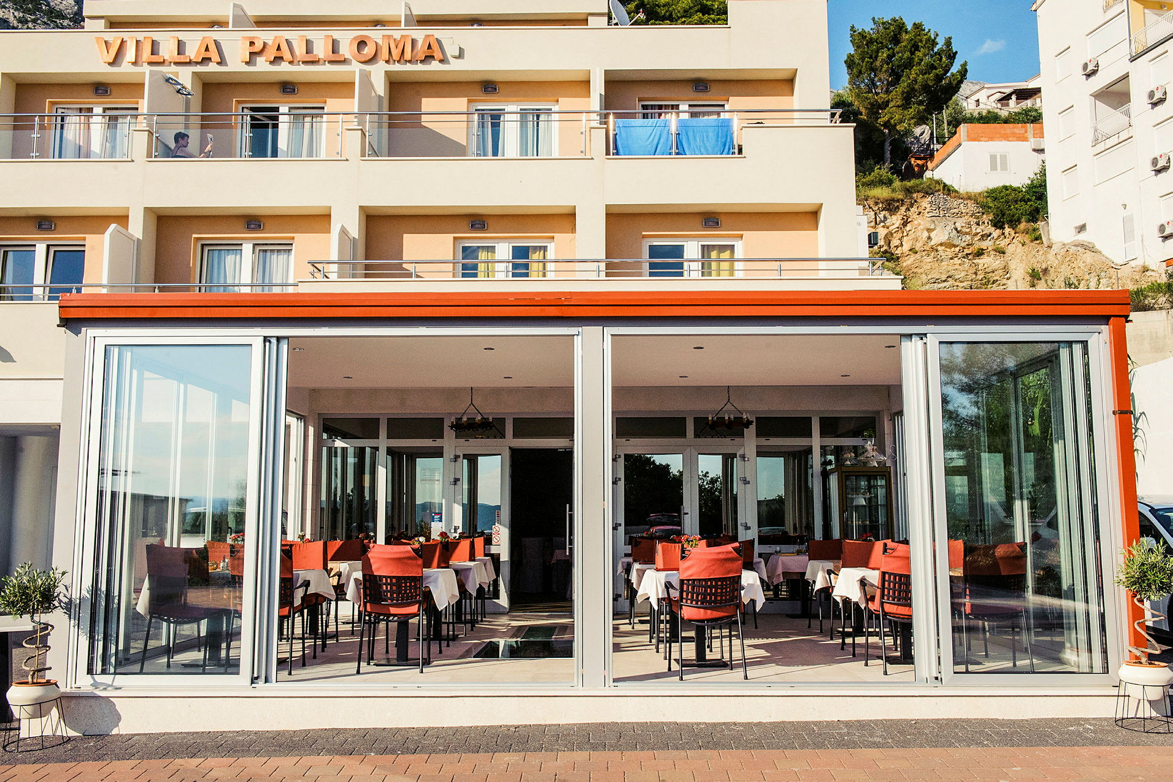 Entrén till Villa Palloma med en restaurang fylld med dukade bord. (AI-genererad text)