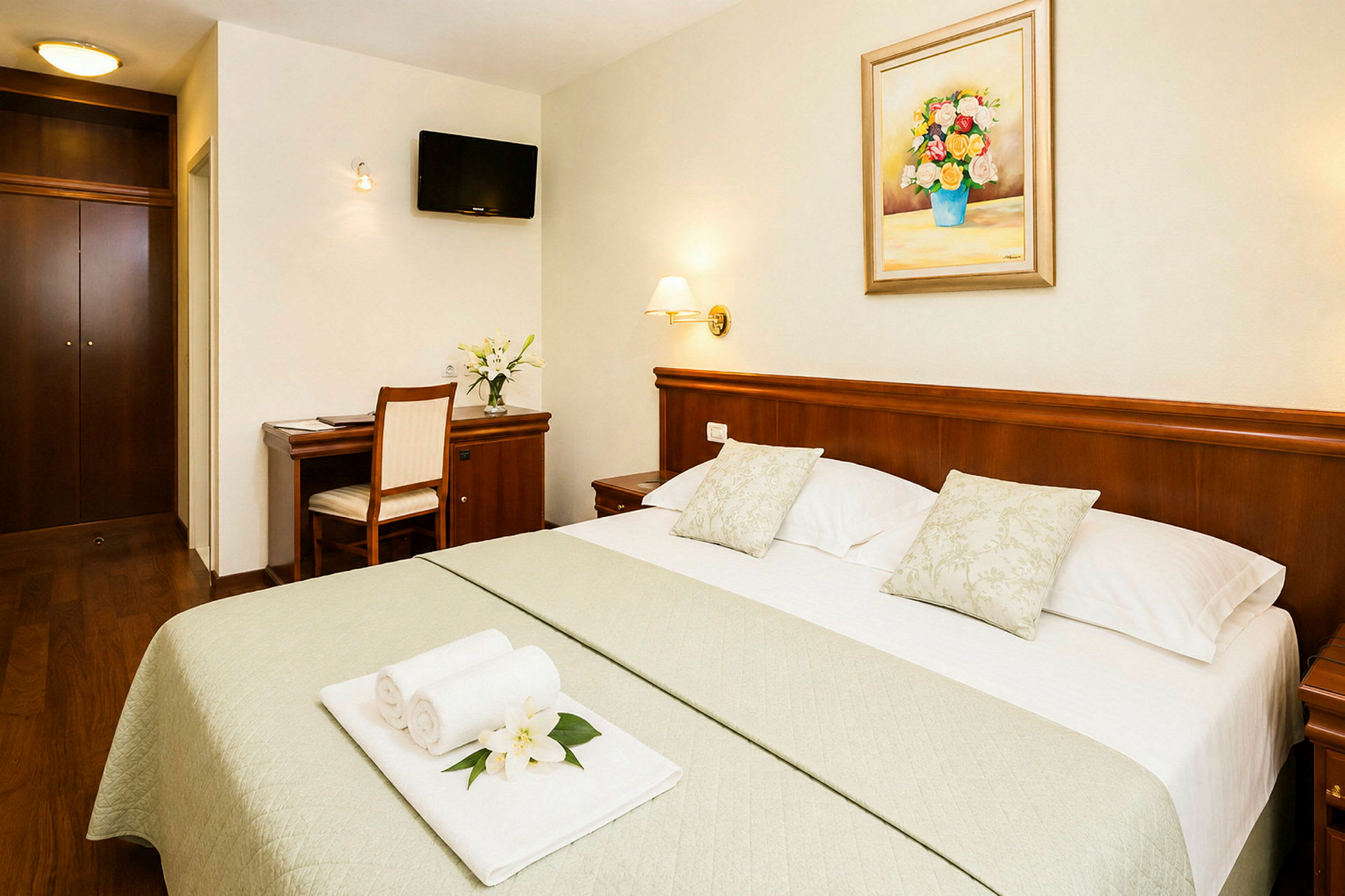 Ett hotellrum med en dubbelsäng, skrivbord och en tavla på väggen. (AI-genererad text)