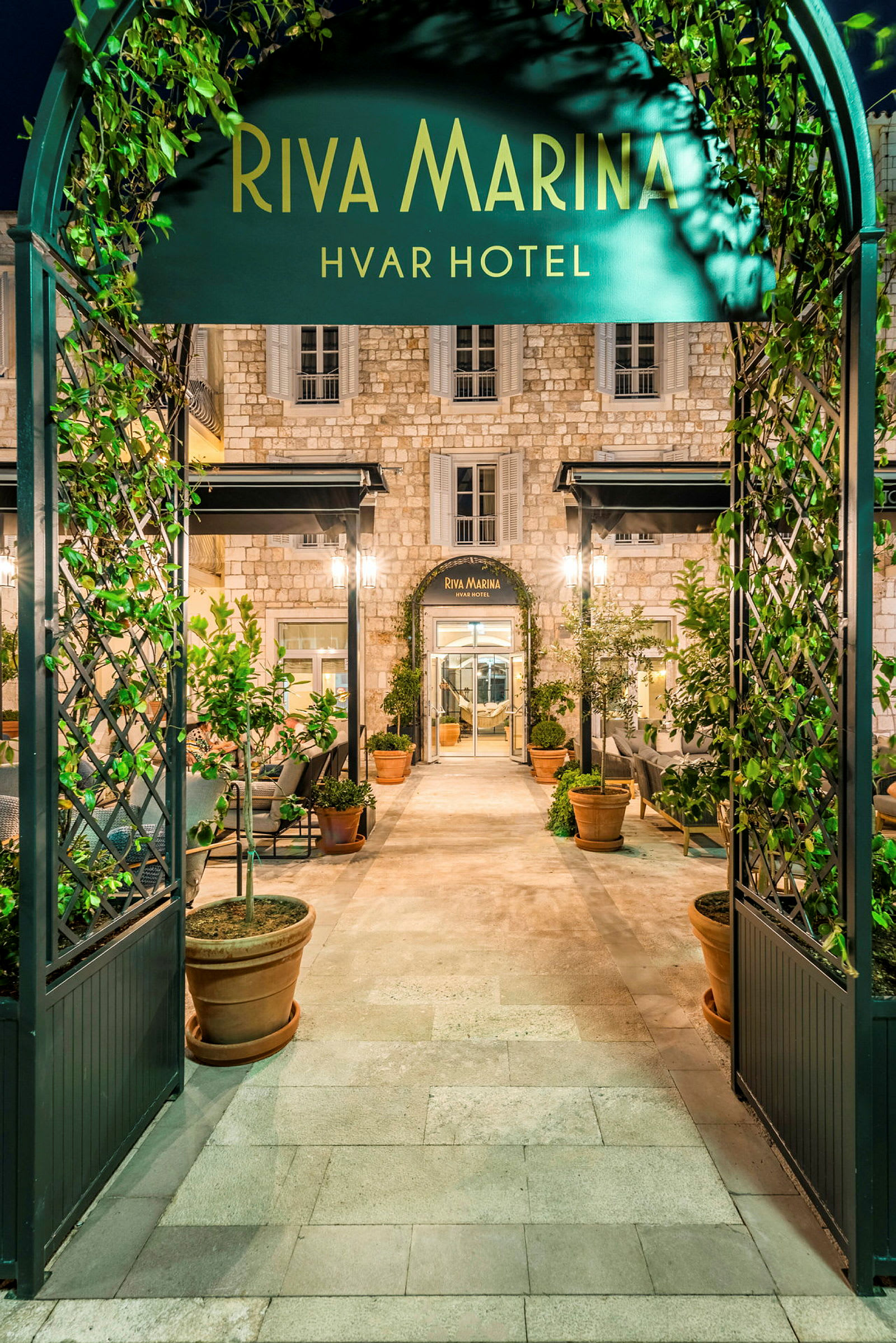 Entré till Riva Marina Hvar Hotel, med grönskande växter och elegant arkitektur. (AI-genererad text)
