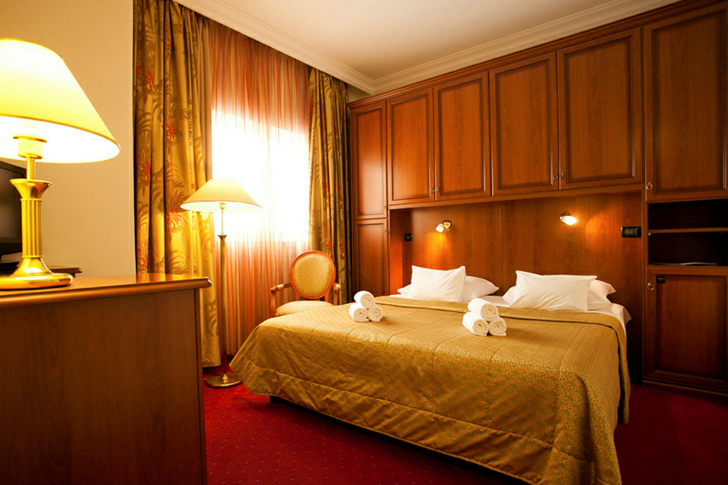 Ett hotellrum med en stor säng, uppvikta handdukar, träpanel i inredningen och mysig belysning. (AI-genererad text)