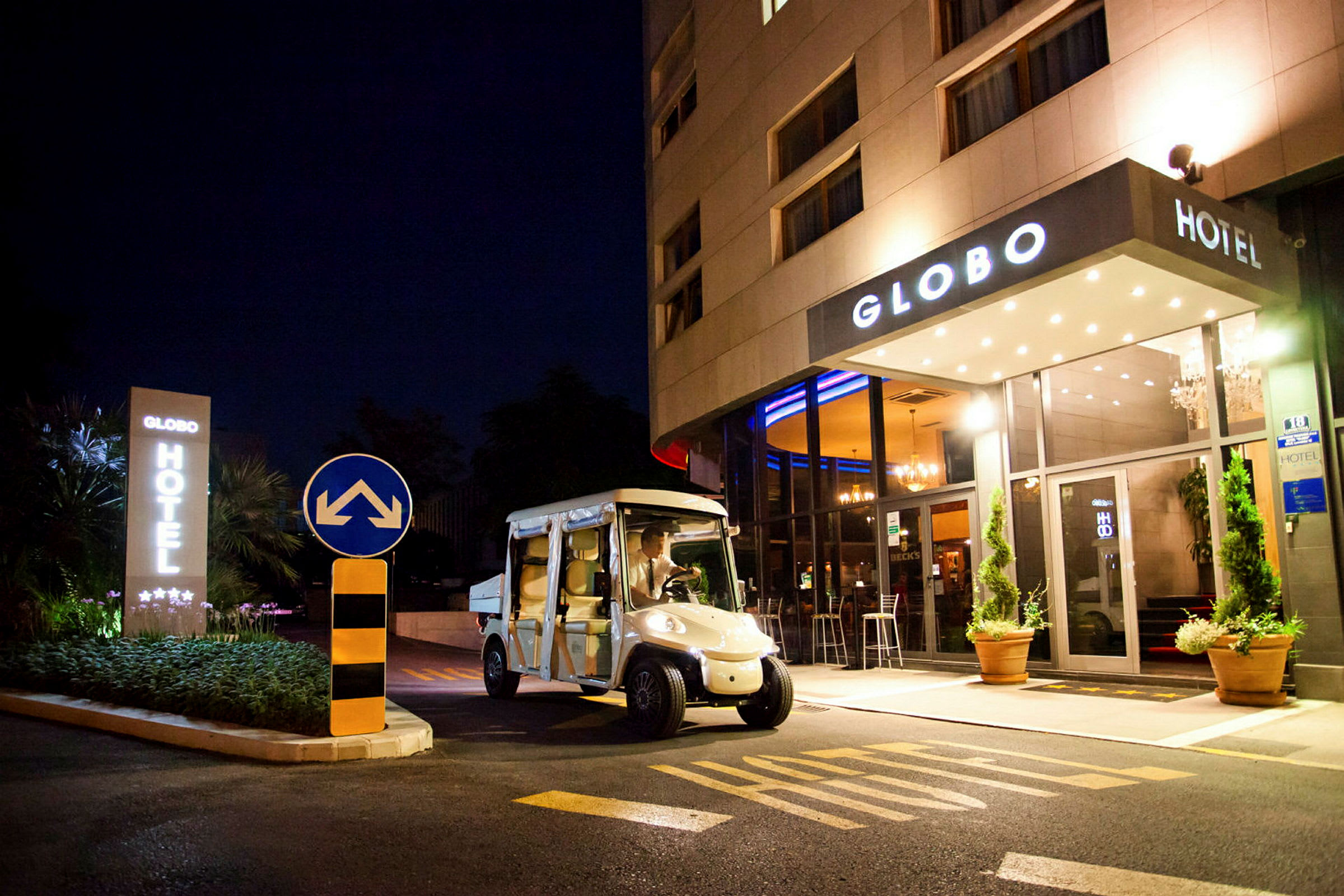Ett hotell sett på natten med namnet Globo, en elbil står parkerad framför ingången. (AI-genererad text)