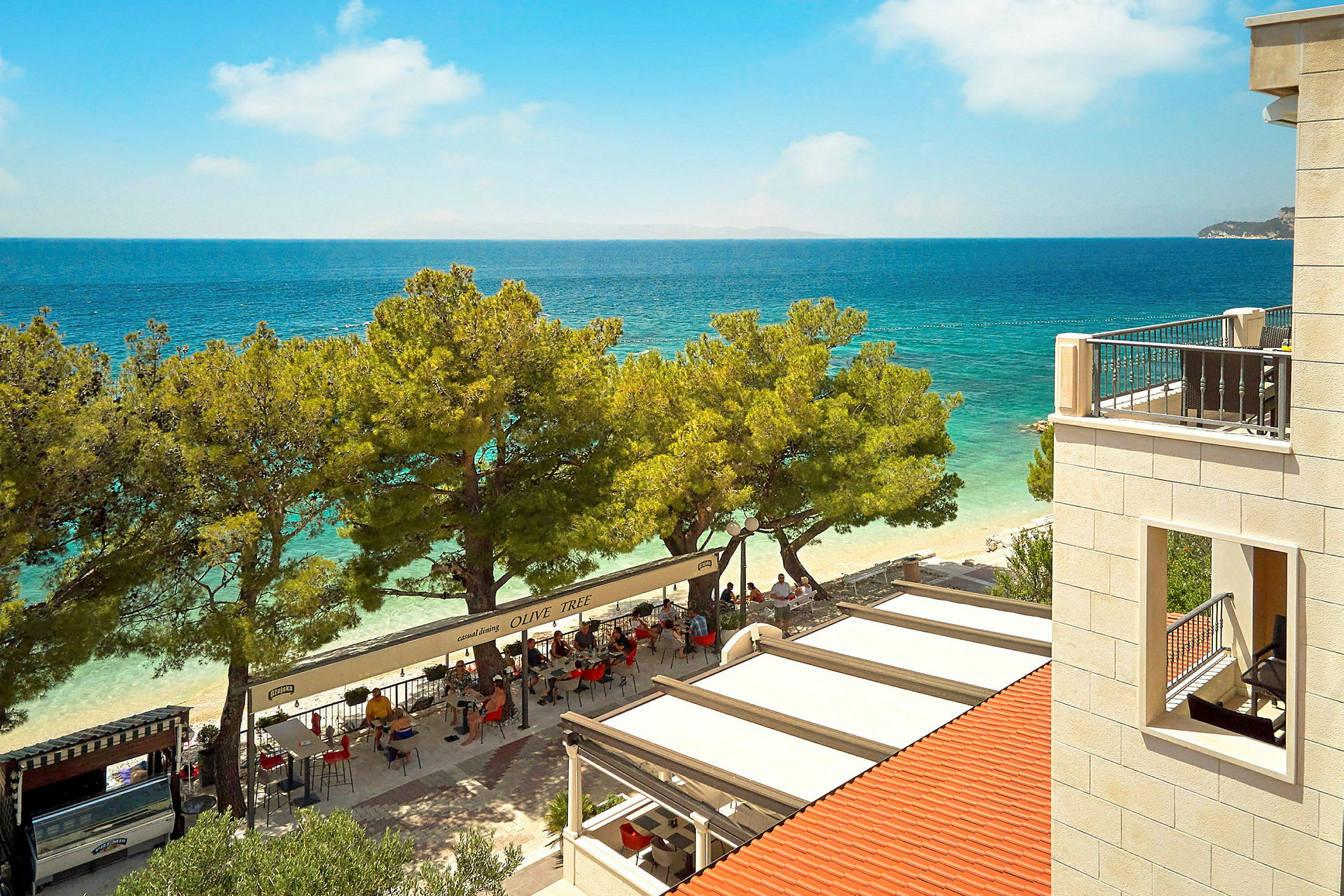 Utsikt över en restaurang vid stranden med havet i bakgrunden. (AI-genererad text)