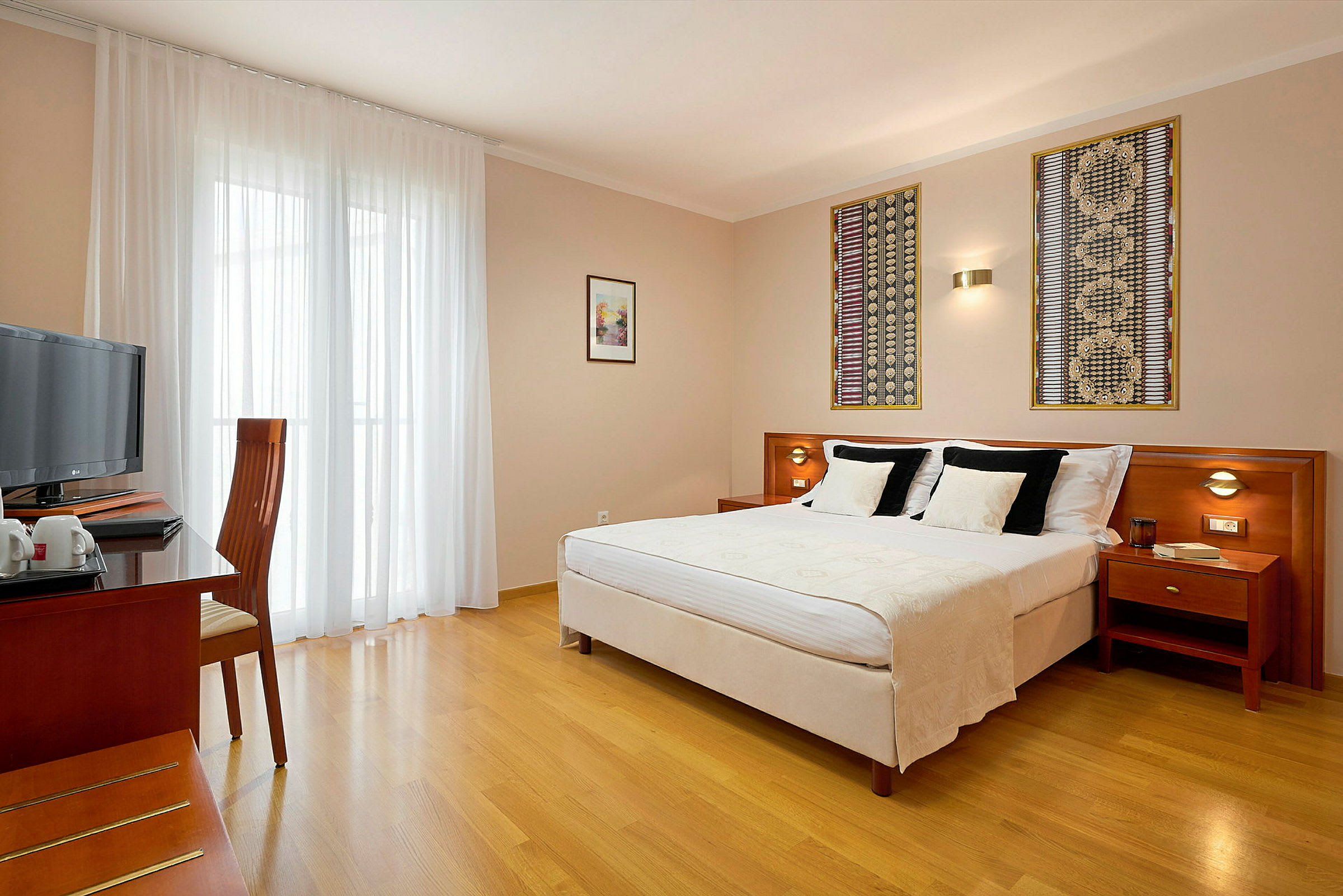 Ett hotellrum med en dubbelsäng, ett skrivbord och en stol samt en TV. (AI-genererad text)