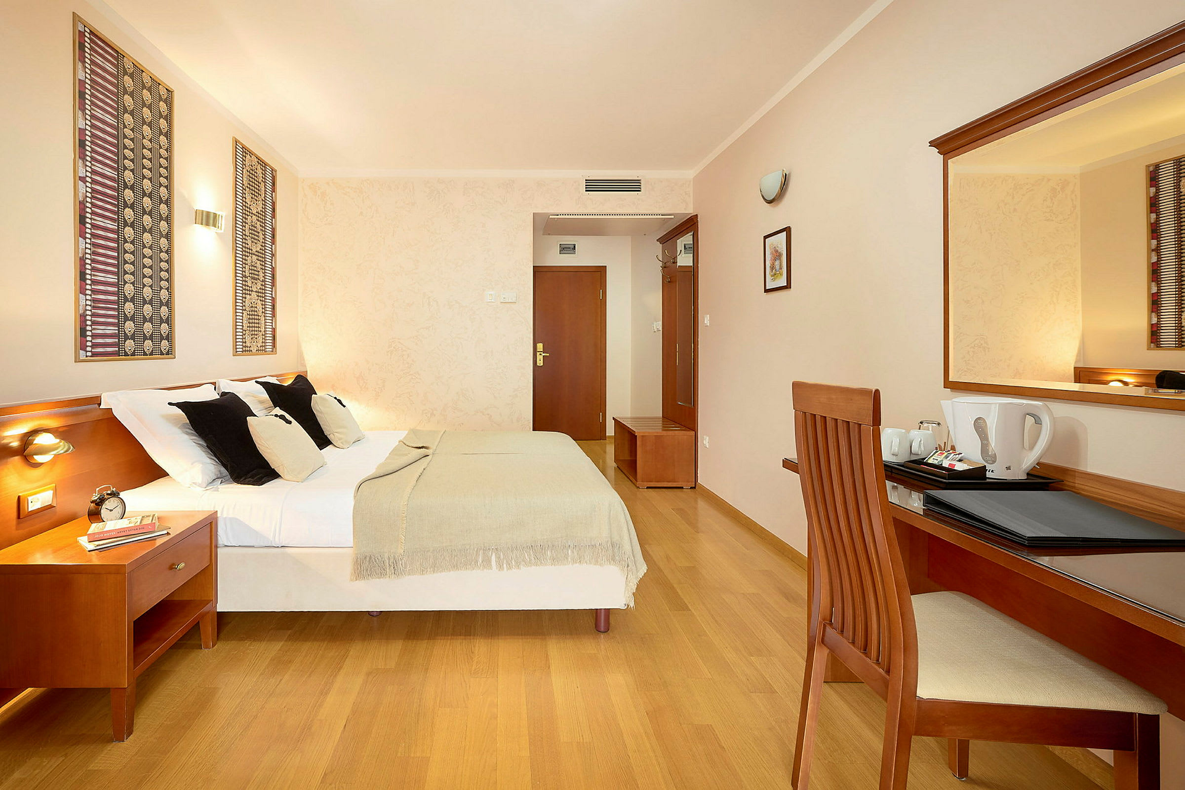 Hotellrum med en dubbelsäng, skrivbord och spegel. (AI-genererad text)