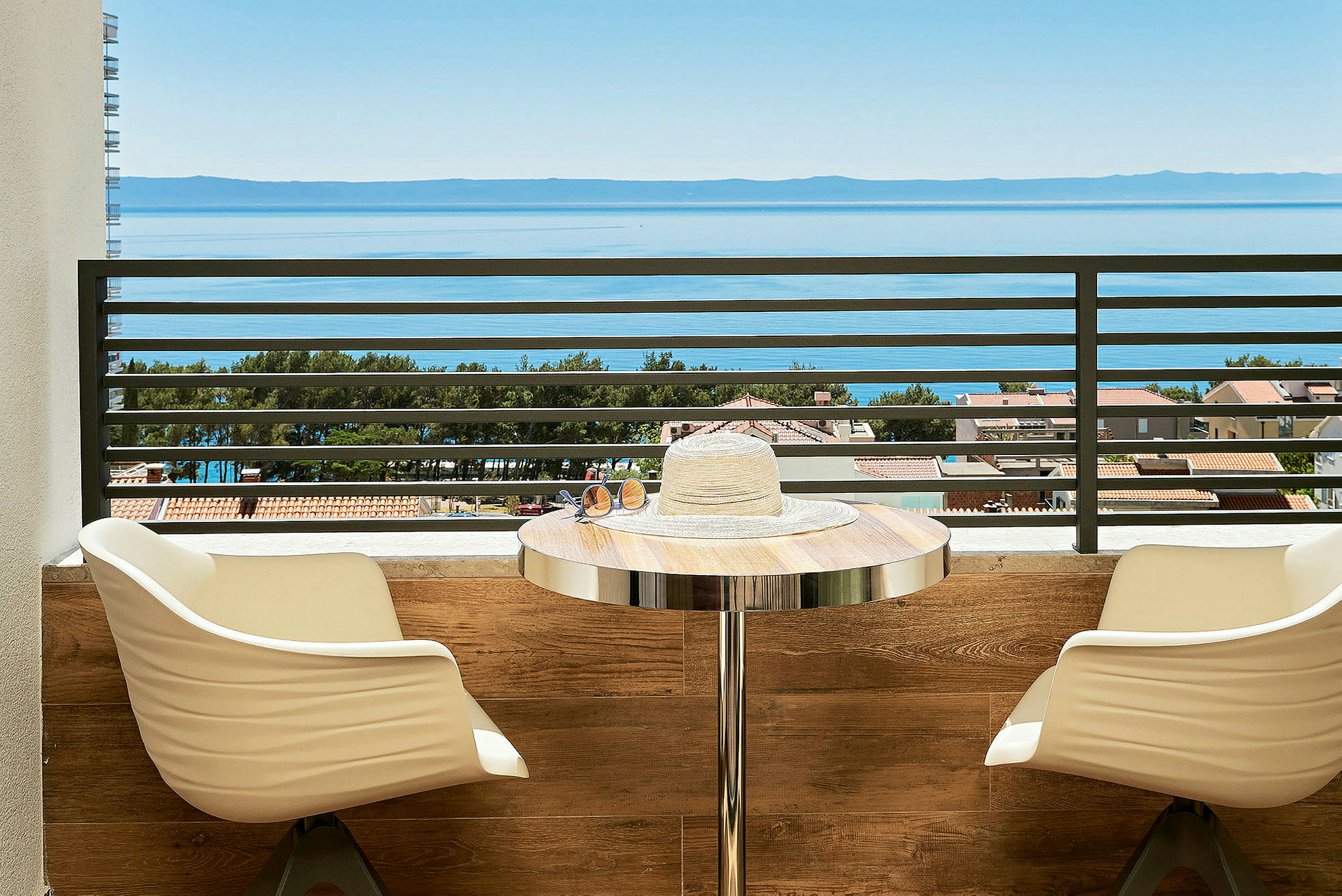Utsikt över havet från en balkong med sittplatser och ett bord. (AI-genererad text)