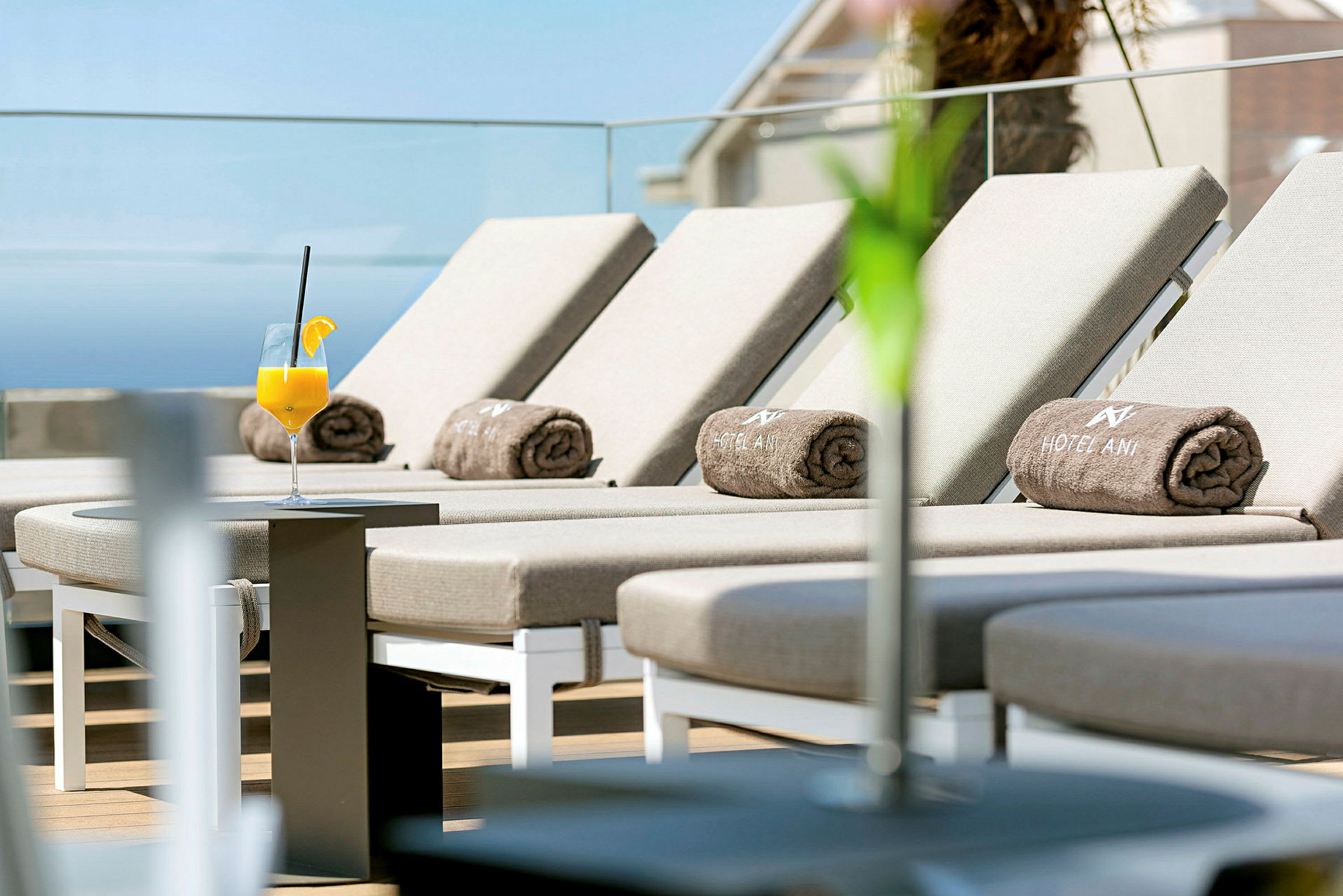 Solstolar med hotellhanddukar på en terrass, ett glas apelsinjuice står på ett bord. (AI-genererad text)