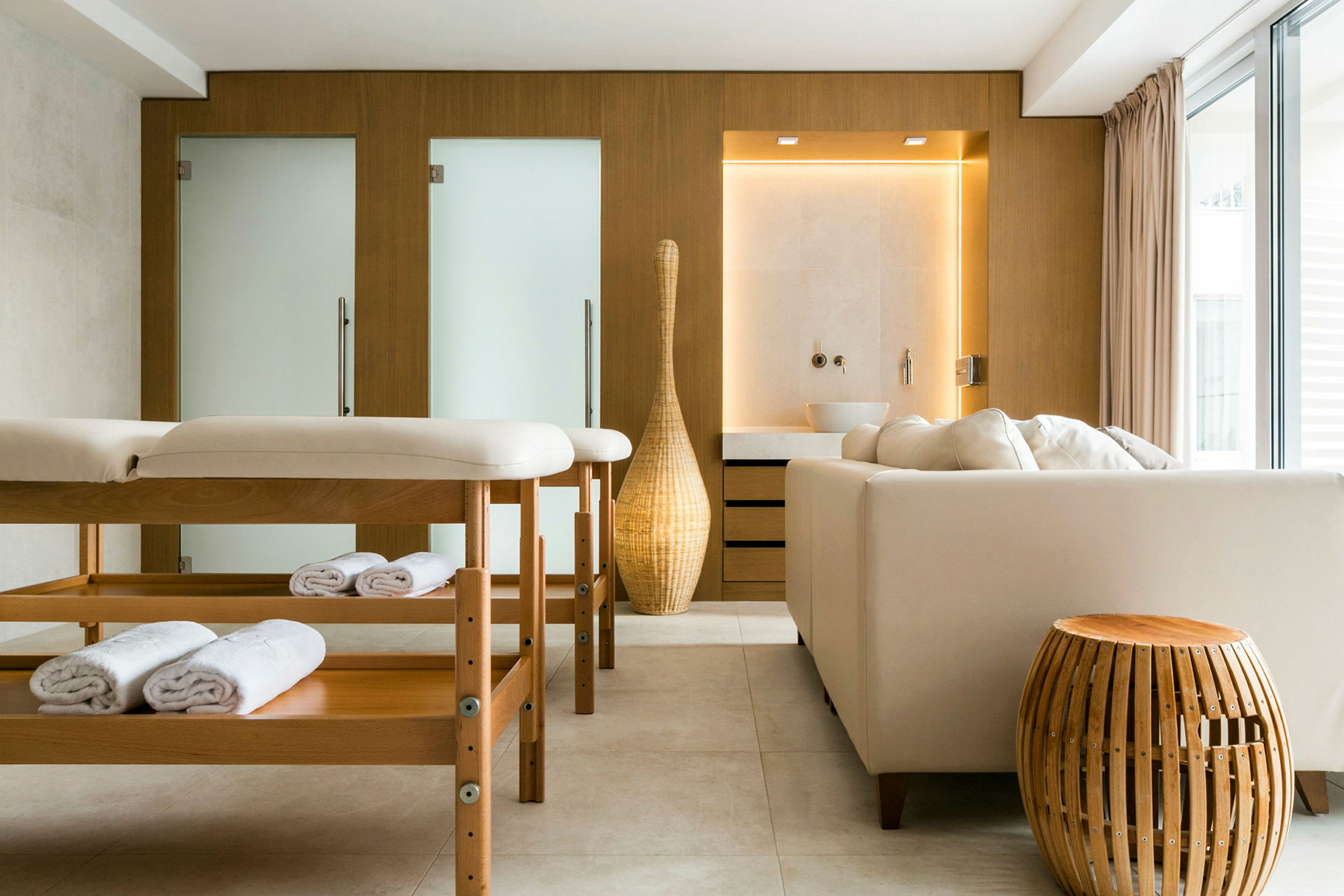Ett modernt inrett rum med en massagebänk, en soffa och harmonisk belysning. (AI-genererad text)