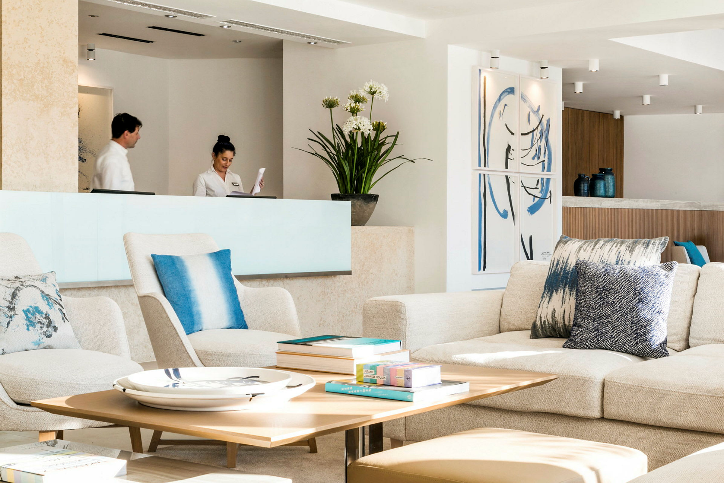 En ljus och modern hotellobby med sittplatser, ett receptionsområde och dekorativa föremål. (AI-genererad text)