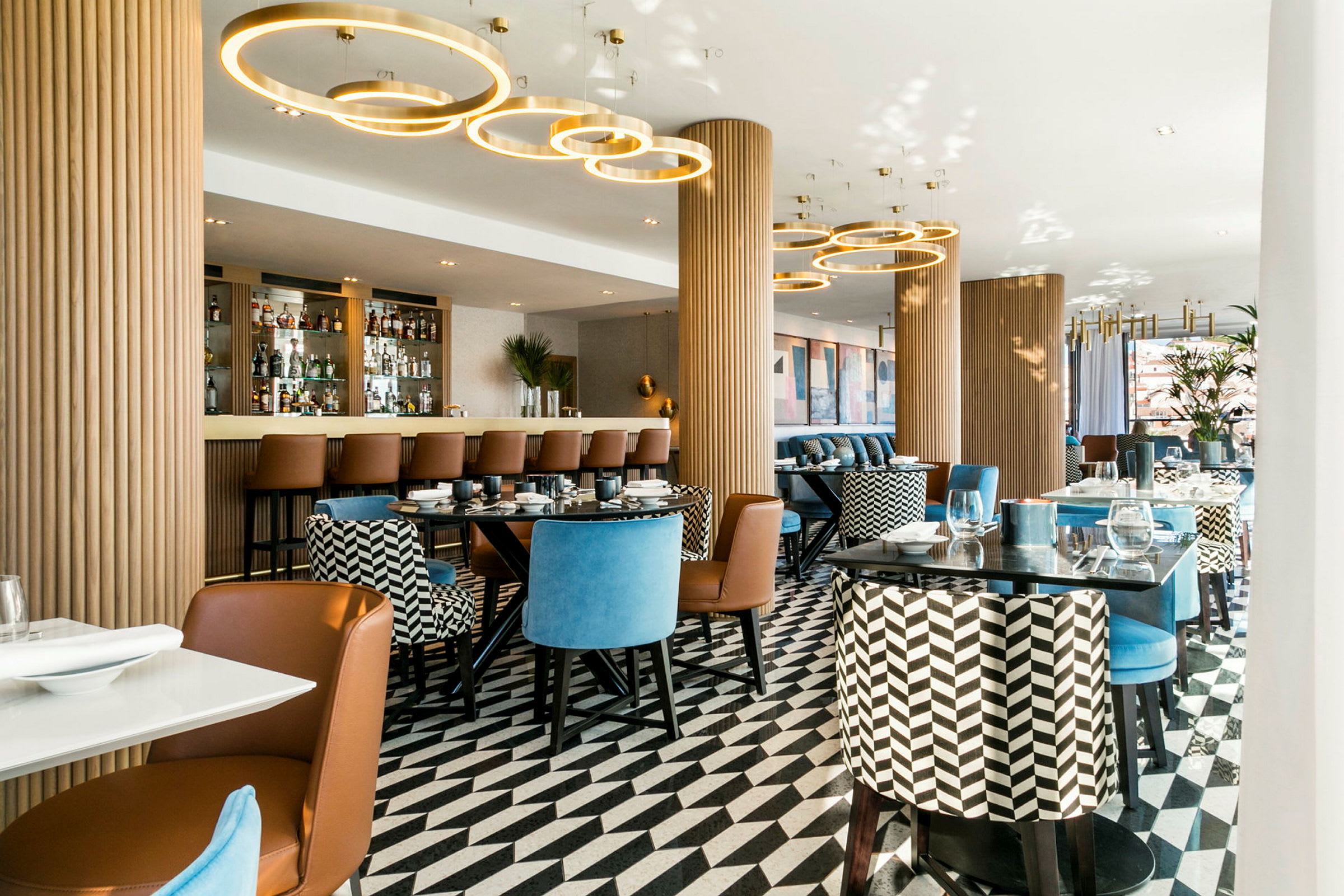 En elegant restaurang med moderna sittmöbler, ett mönstrat golv och en bardisk i bakgrunden. (AI-genererad text)