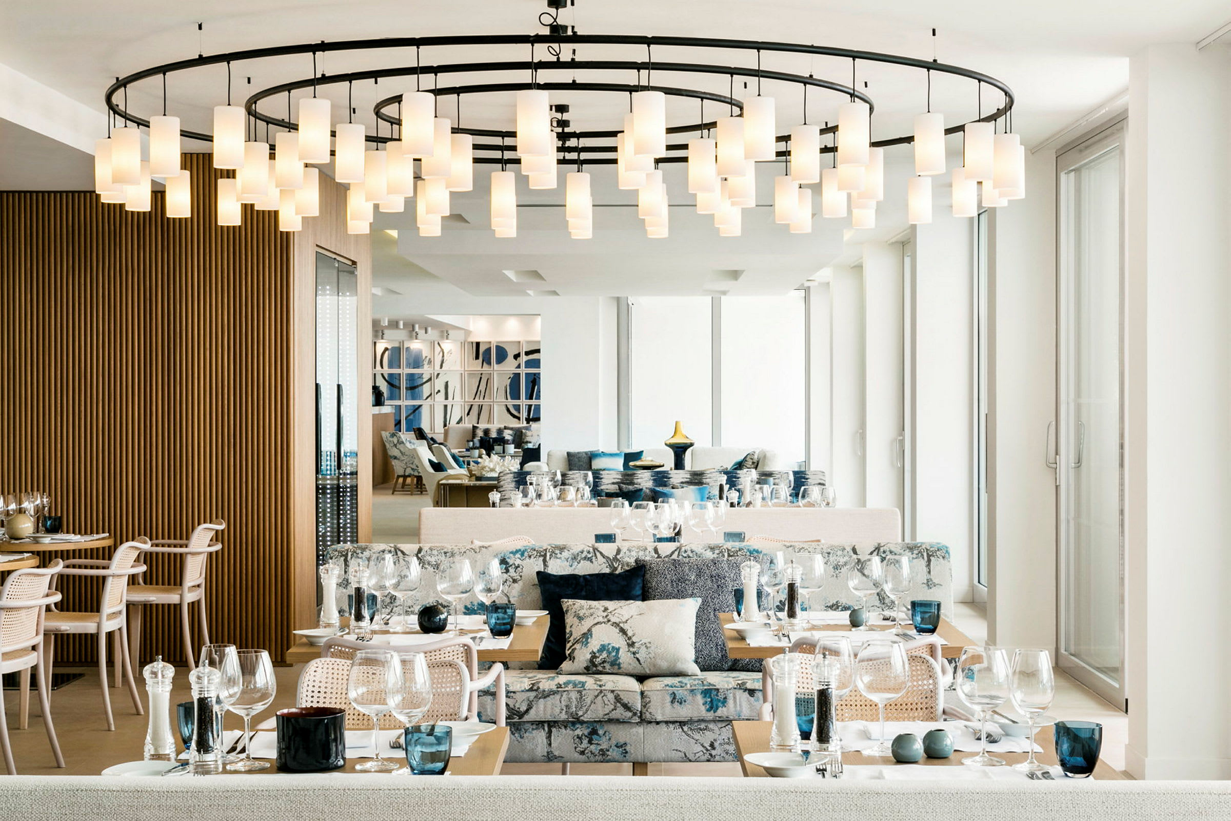 Interiör av en elegant restaurang med dukade bord, moderna stolar och en hängande ljuskrona i taket. (AI-genererad text)