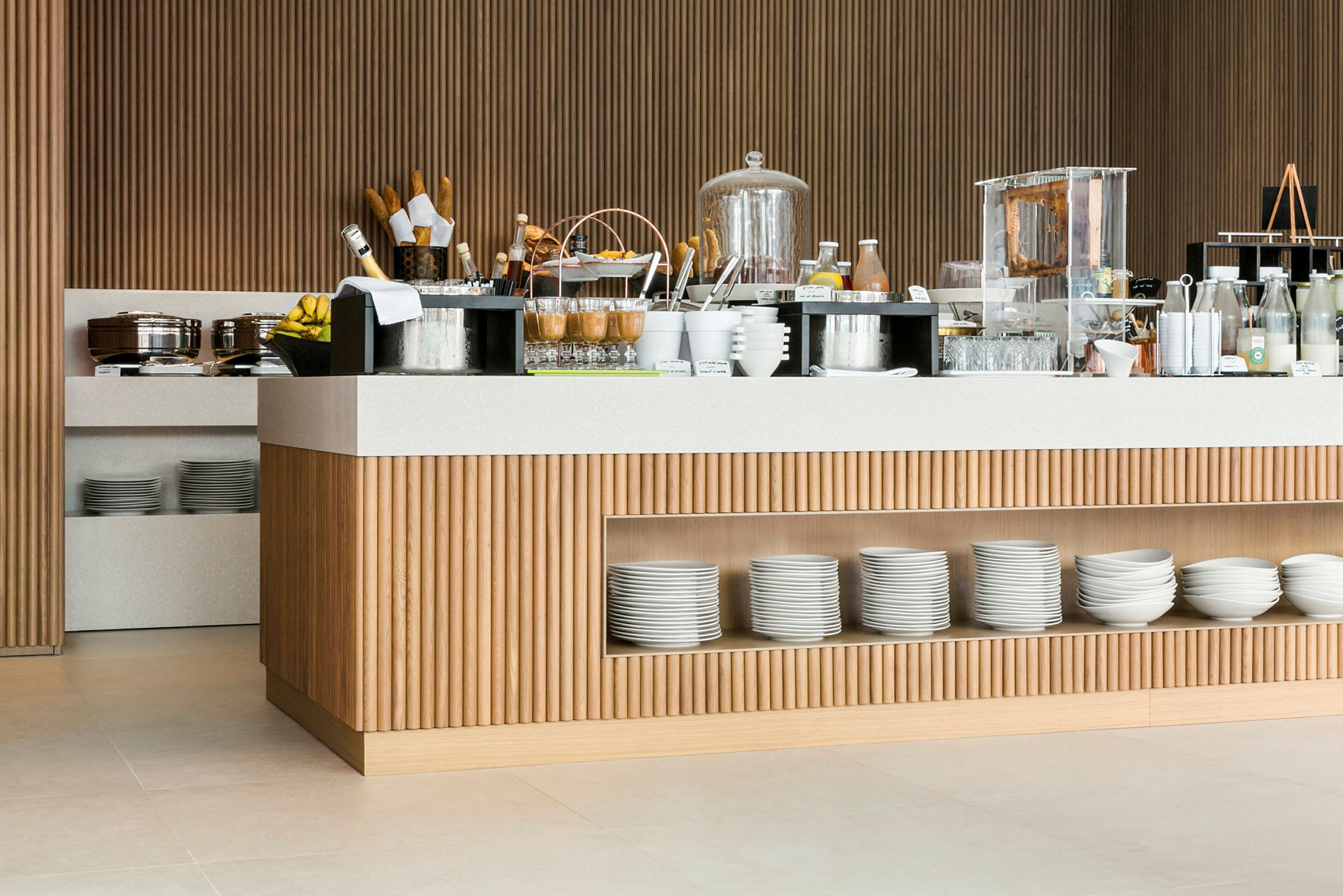 Frukostbuffé med olika anrättningar och drycker på ett modernt serveringsbord av trä och ljusa detaljer. (AI-genererad text)