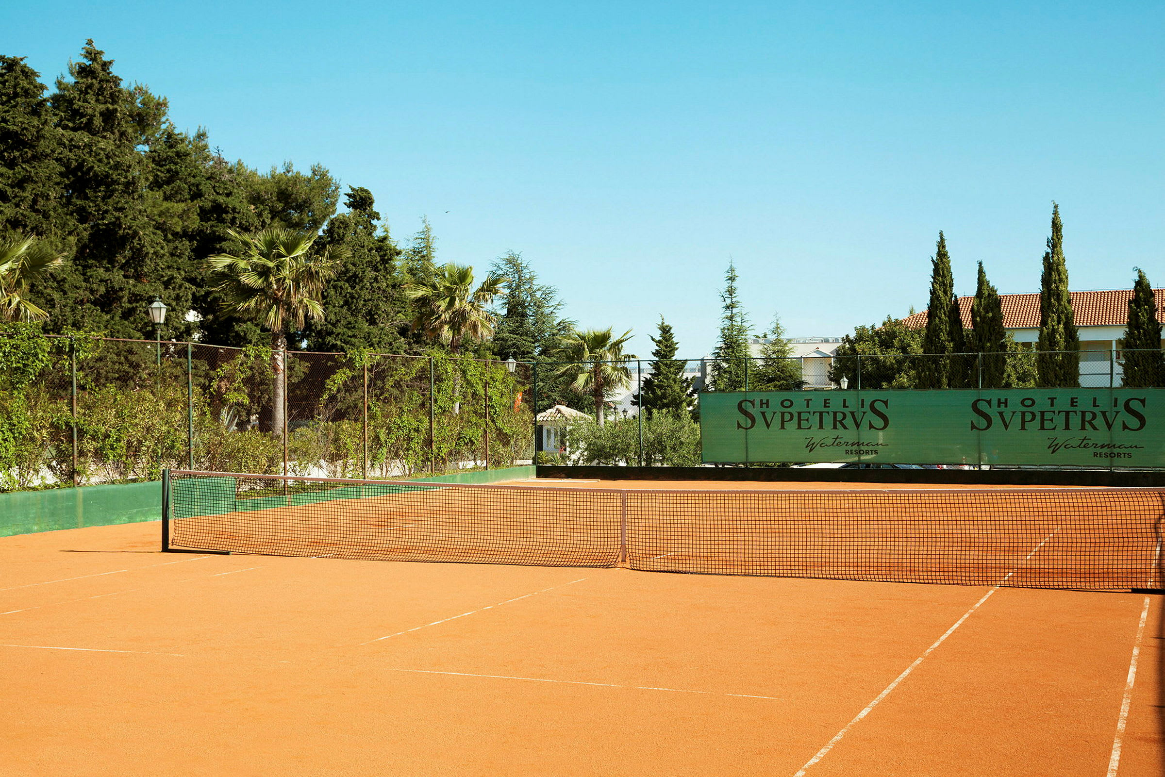 Tennisbana med omgivande träd och buskar. (AI-genererad text)