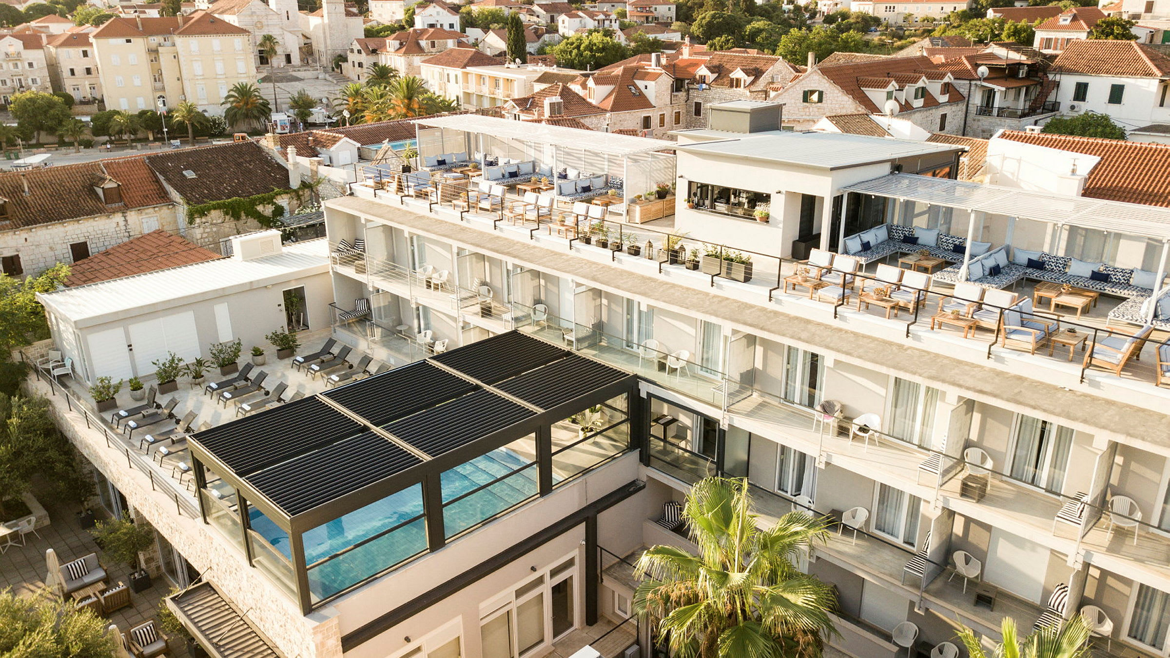 Hotellbyggnad med pool, terrass och omgivande hus. (AI-genererad text)