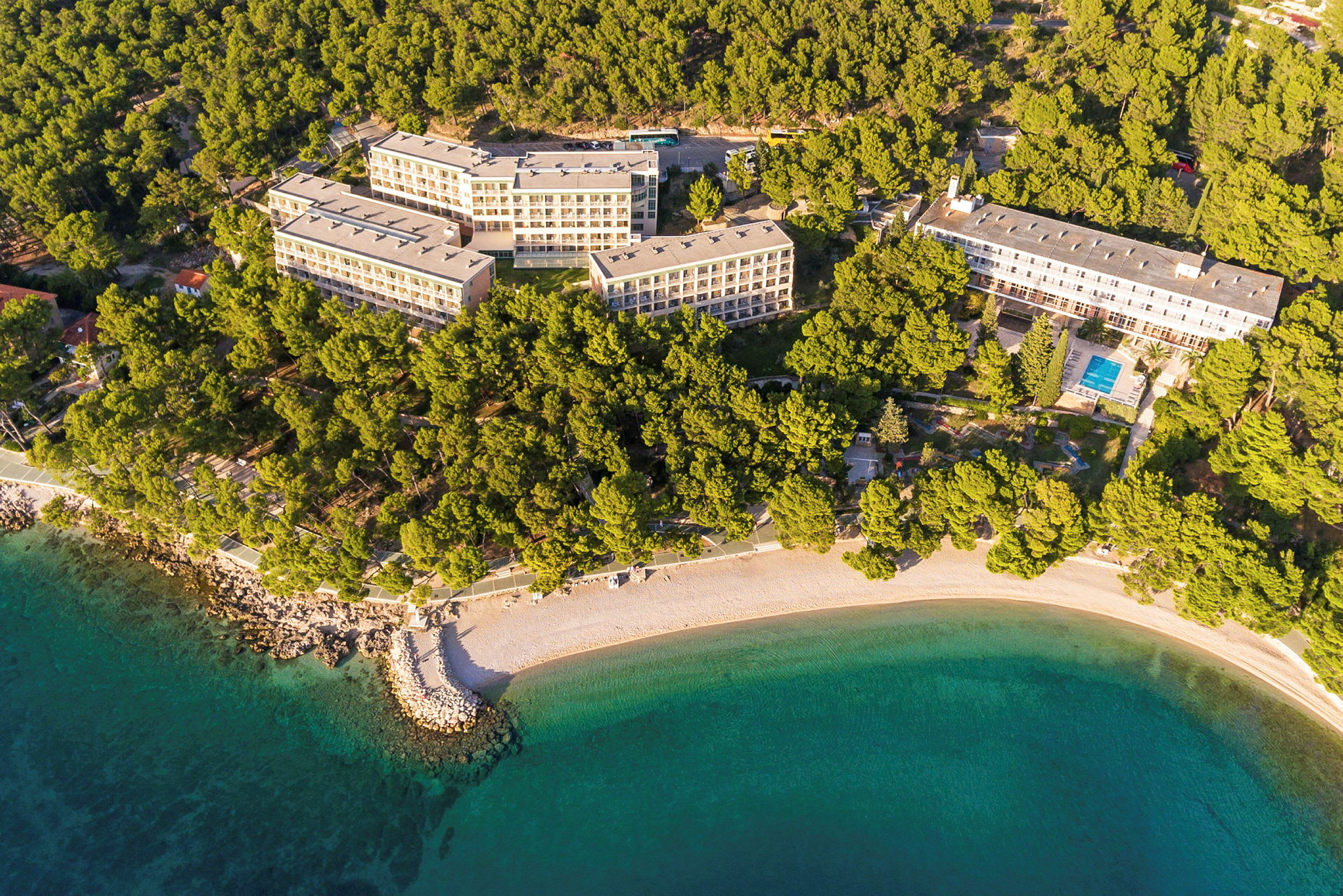 Hotell omgivna av grönska nära en strand. (AI-genererad text)