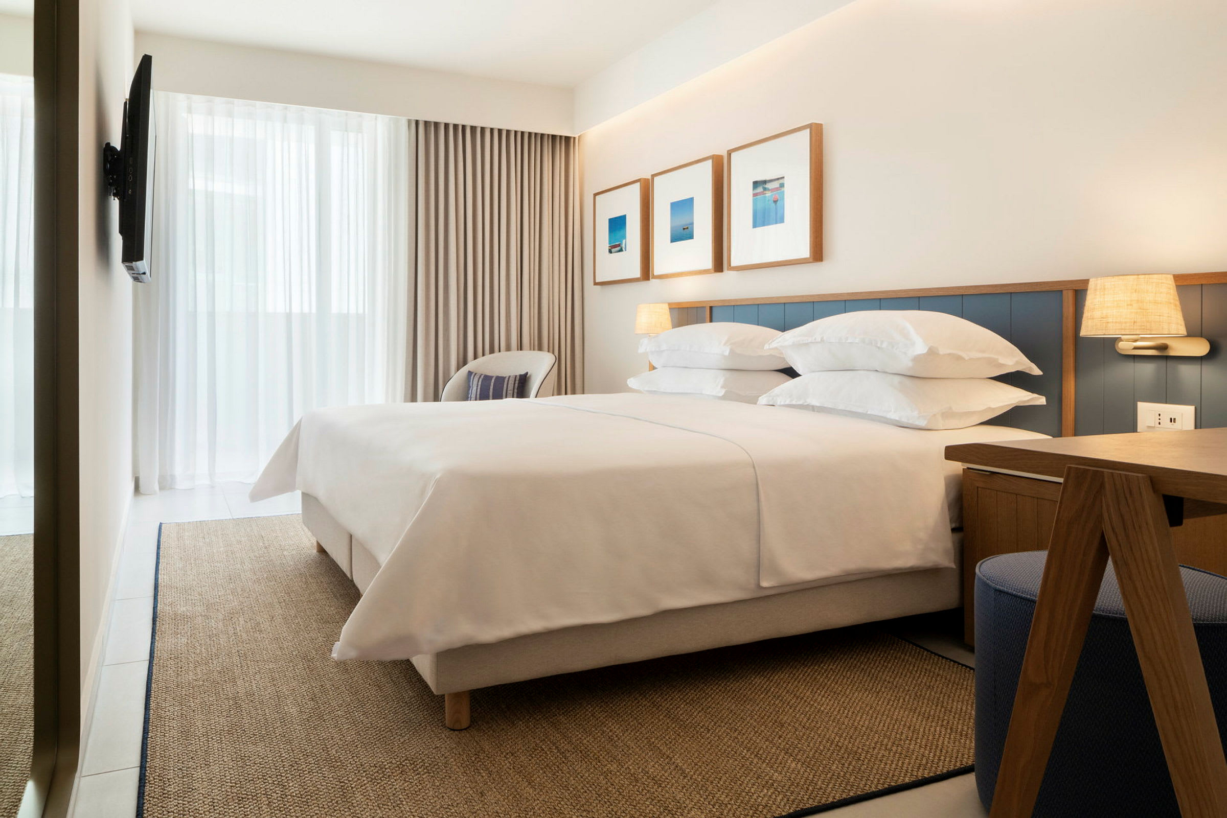Ett hotellrum med en stor dubbelsäng, väggdekorationer och ett skrivbord. (AI-genererad text)