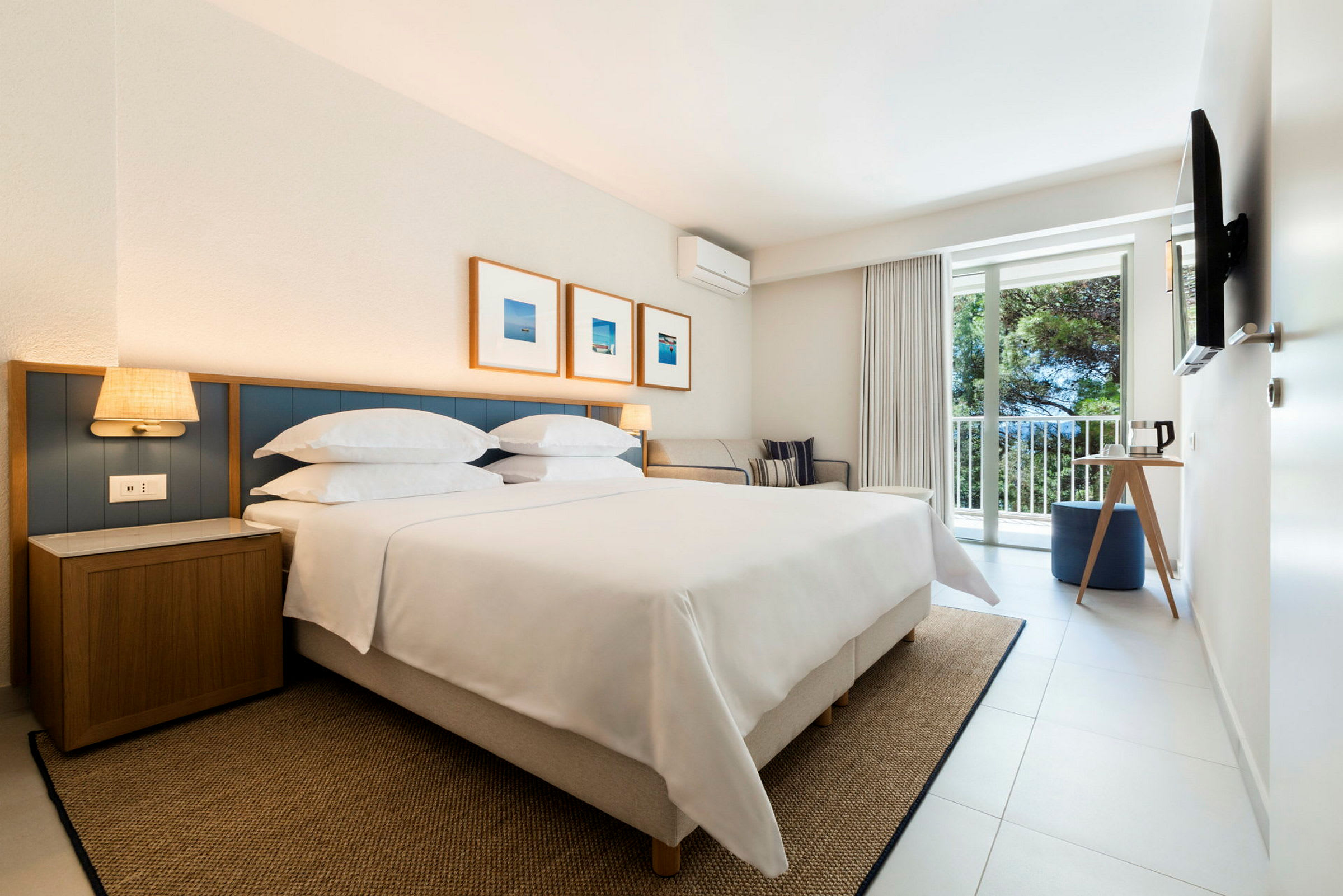 Ett hotellrum med en stor säng, väggdekorationer, en sittgrupp och ett fönster med utsikt. (AI-genererad text)