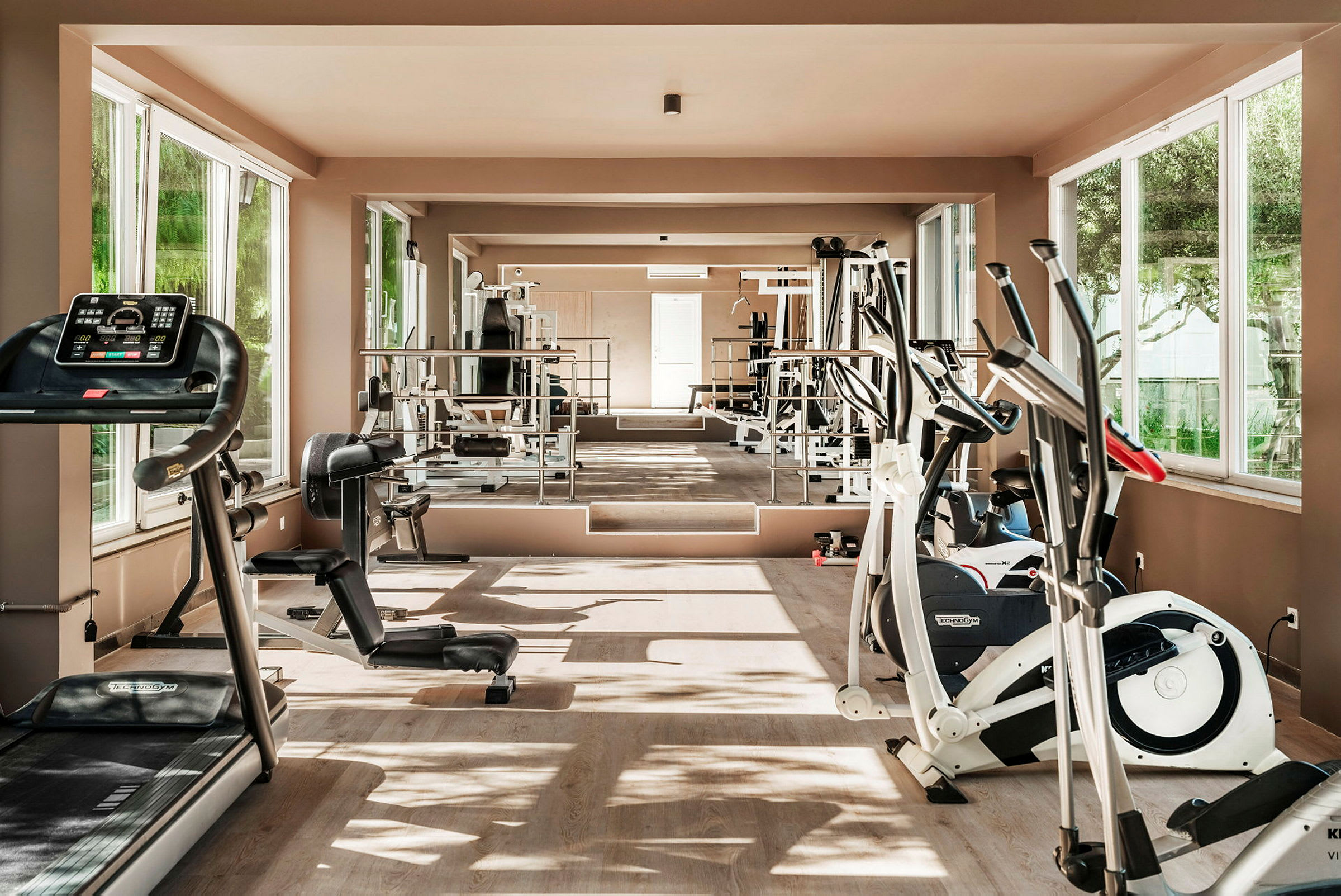 Ett ljust gym med olika träningsmaskiner såsom löpband, träningscyklar och styrketräningsutrustning. (AI-genererad text)