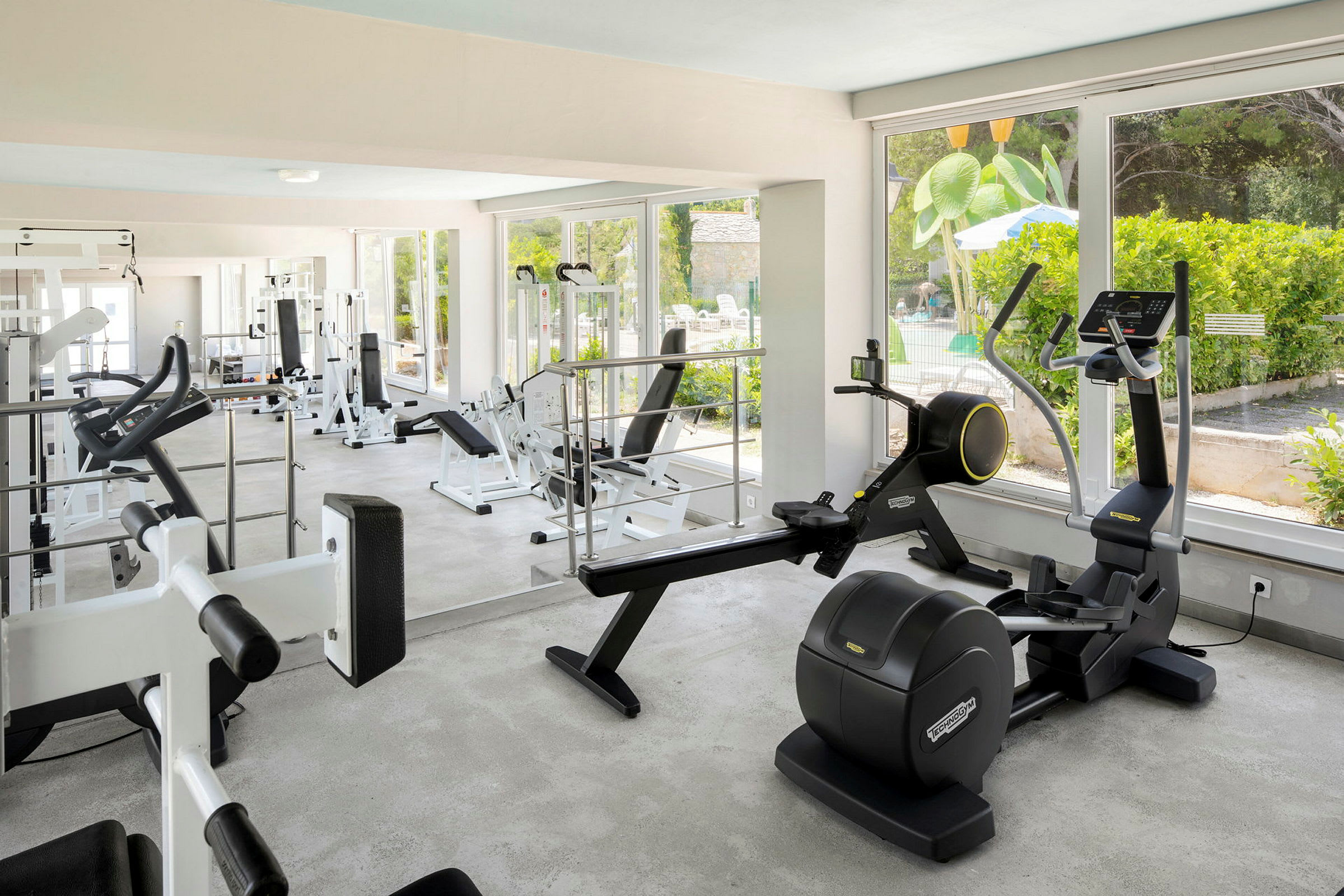 Bild av ett gym med träningsmaskiner och stora fönster. (AI-genererad text)