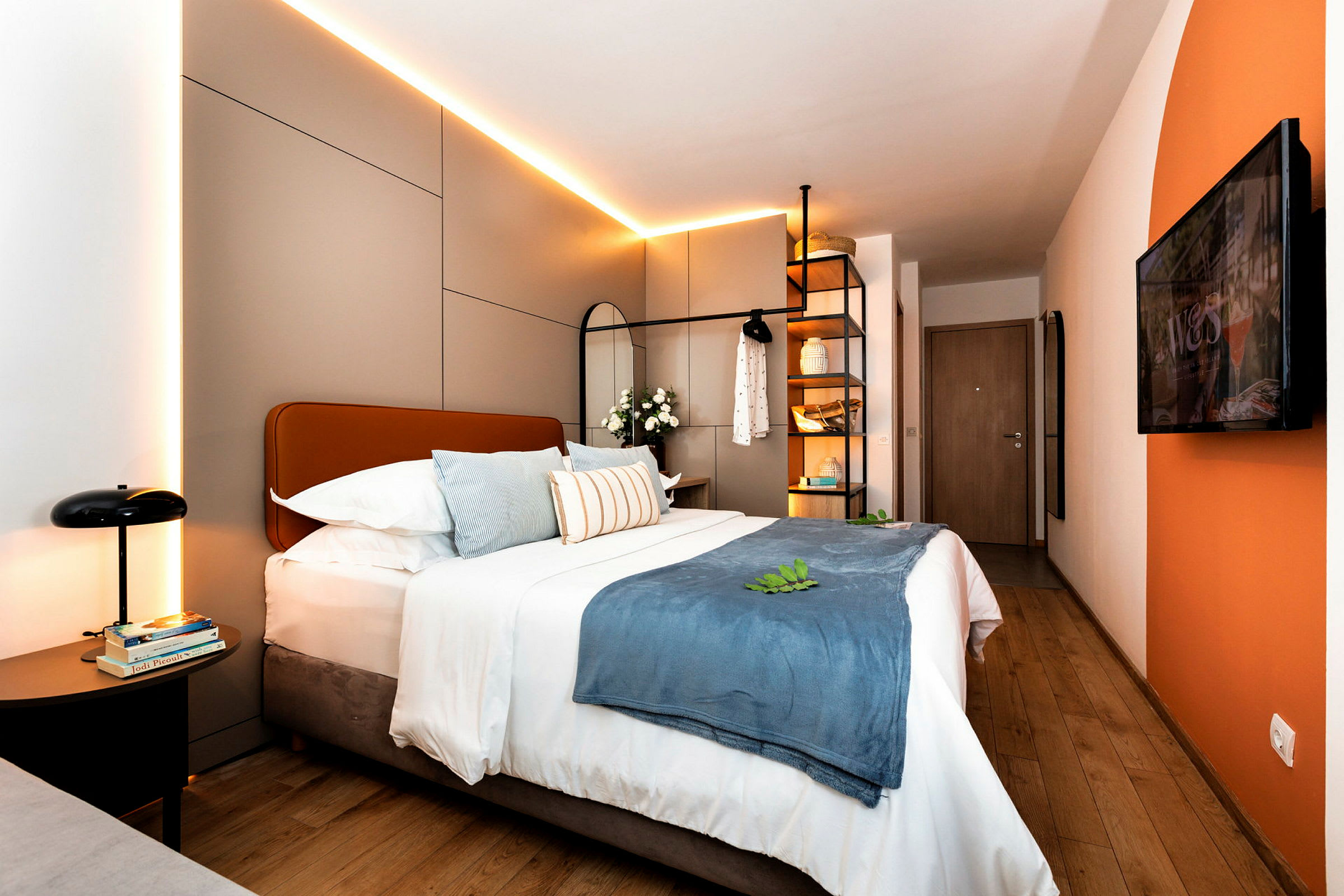 Modernt hotellrum med dubbelsäng, dekorativa kuddar och belysning. (AI-genererad text)