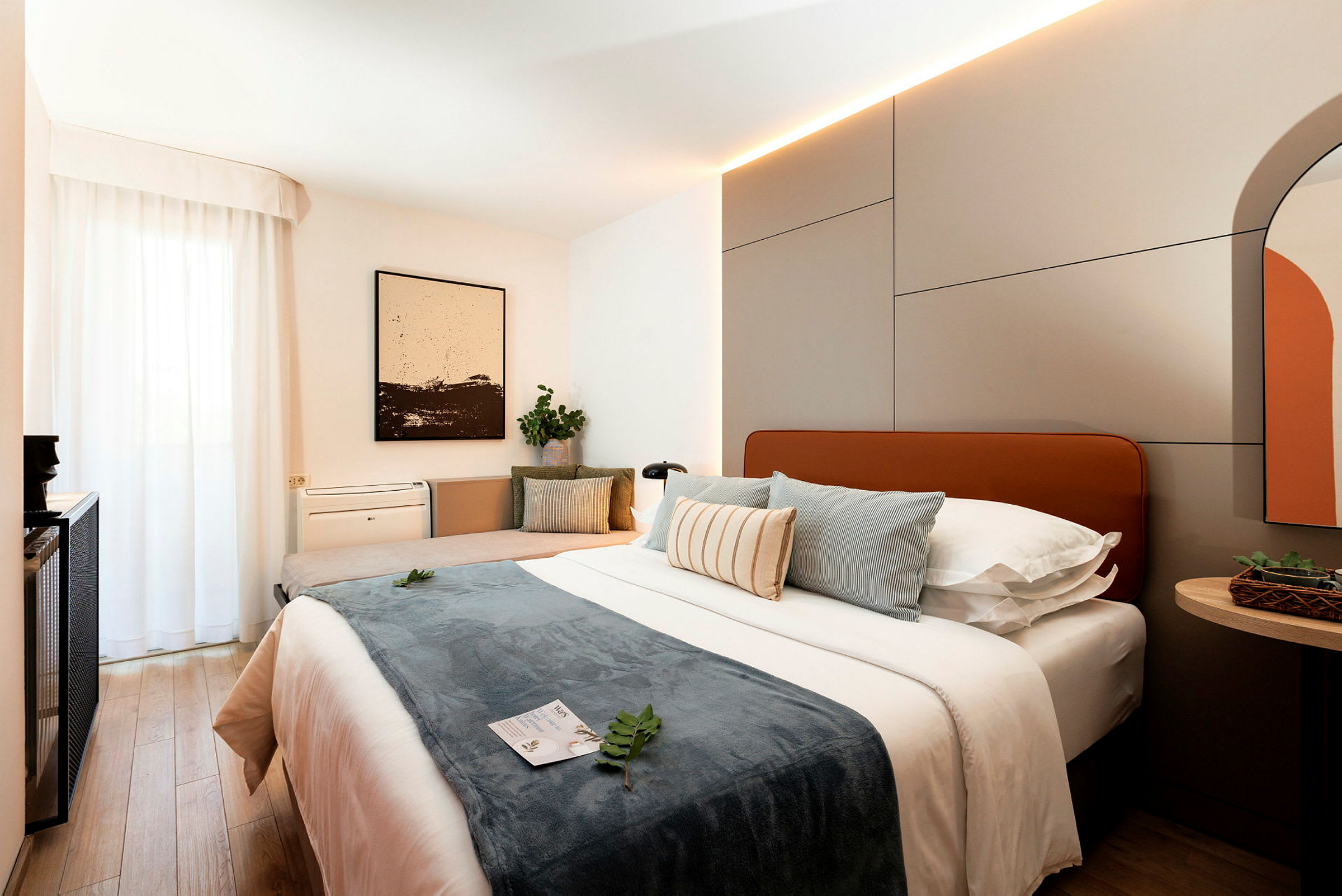 Ett modernt hotellrum med en stor säng, kuddar och inredningsdetaljer. (AI-genererad text)