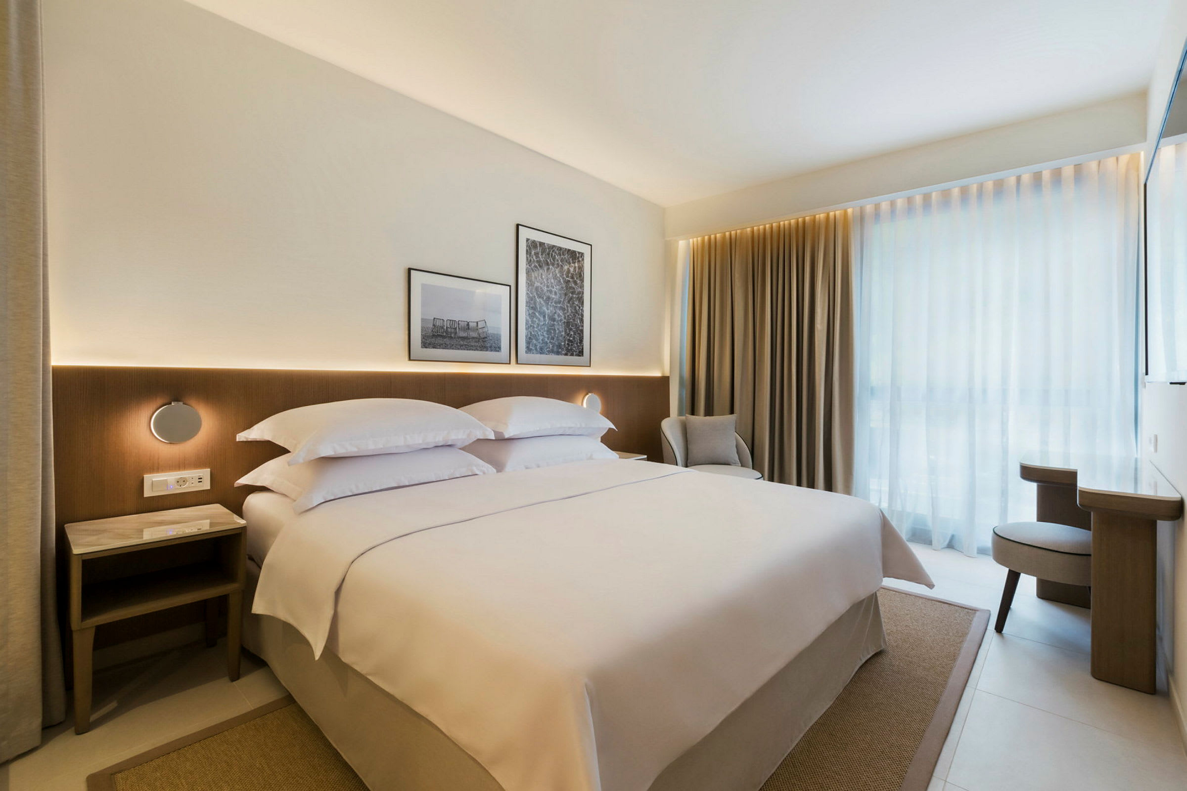 Modernt hotellrum med en stor säng, gardiner och ljus inredning. (AI-genererad text)