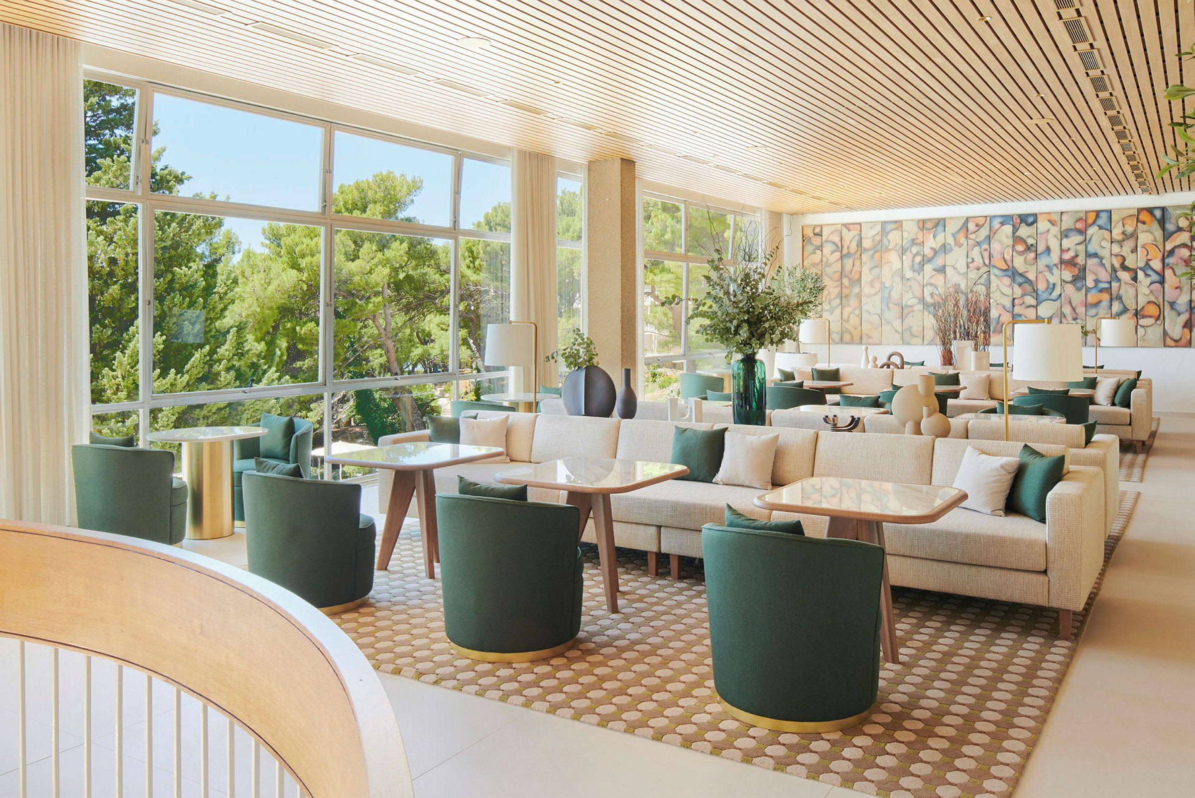 En ljus och modern lounge med gröna möbler, stora fönster och väggkonst. (AI-genererad text)