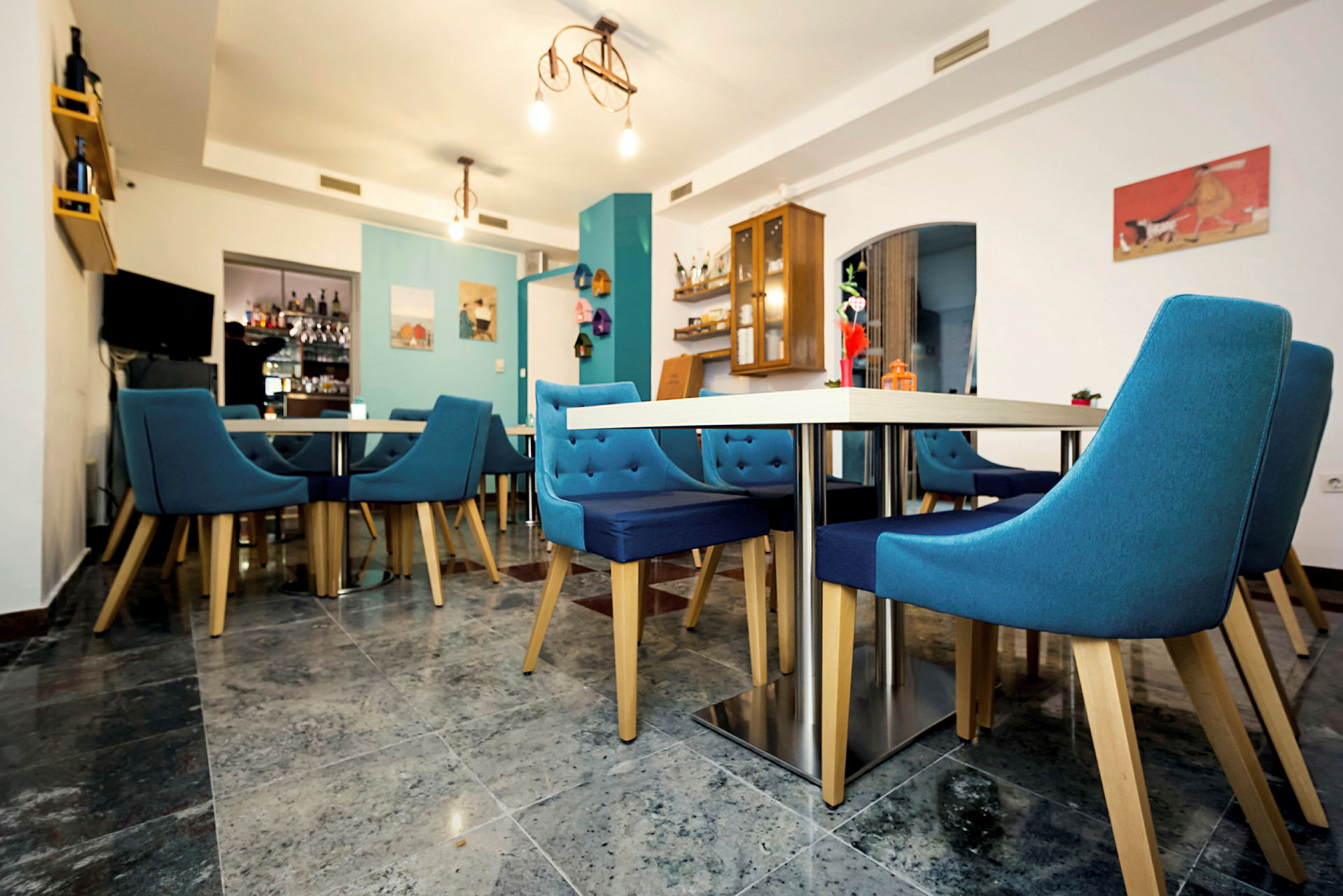 En restauranginteriör med blå stolar och bord. (AI-genererad text)