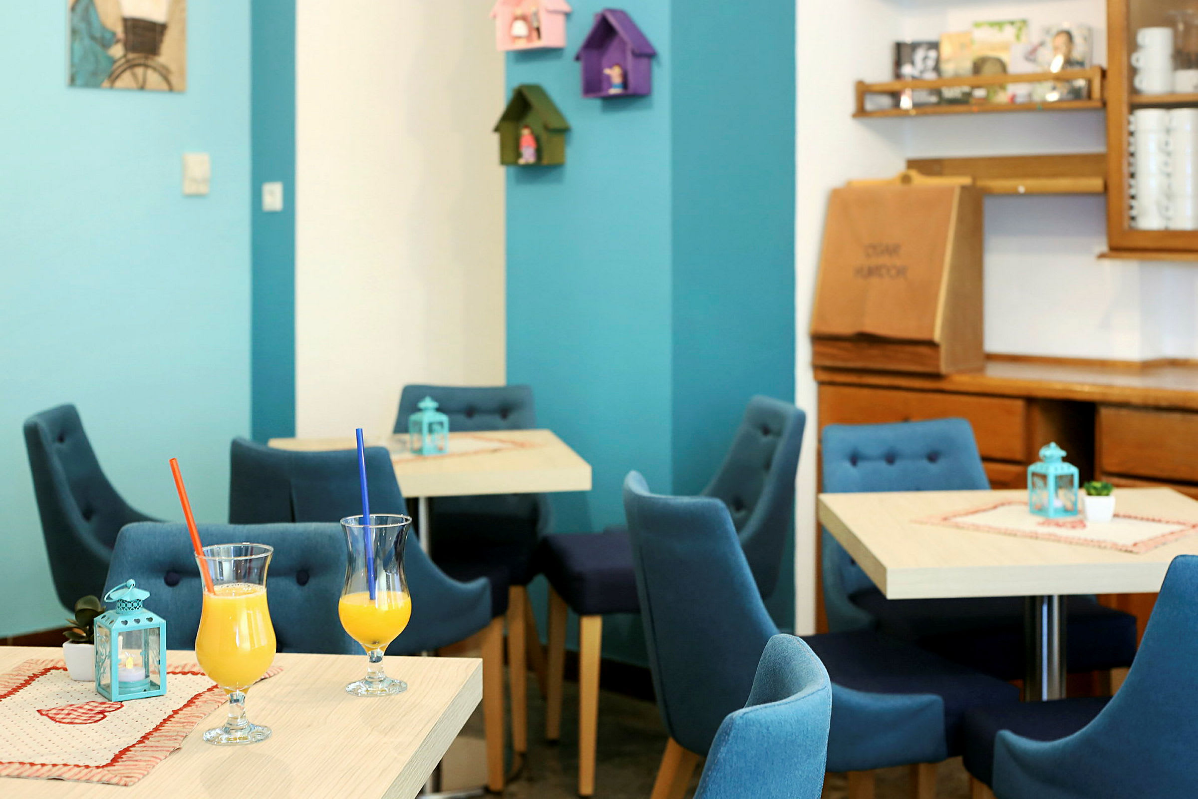 Interiör av ett kafé med blå stolar och glas med uppfriskande drycker på borden. (AI-genererad text)