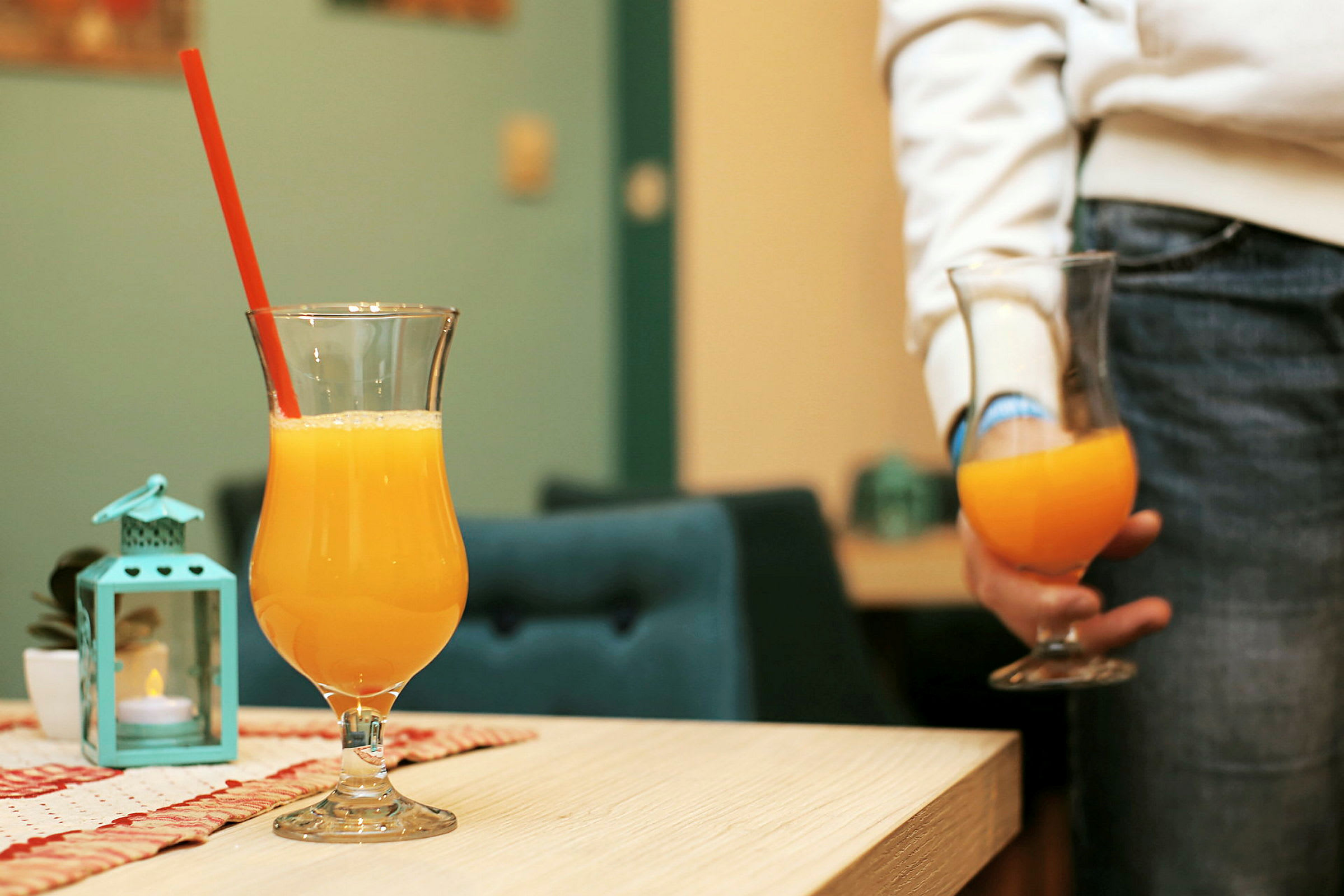 Två glas med apelsinjuice, ett på ett bord och ett hålls i handen. (AI-genererad text)