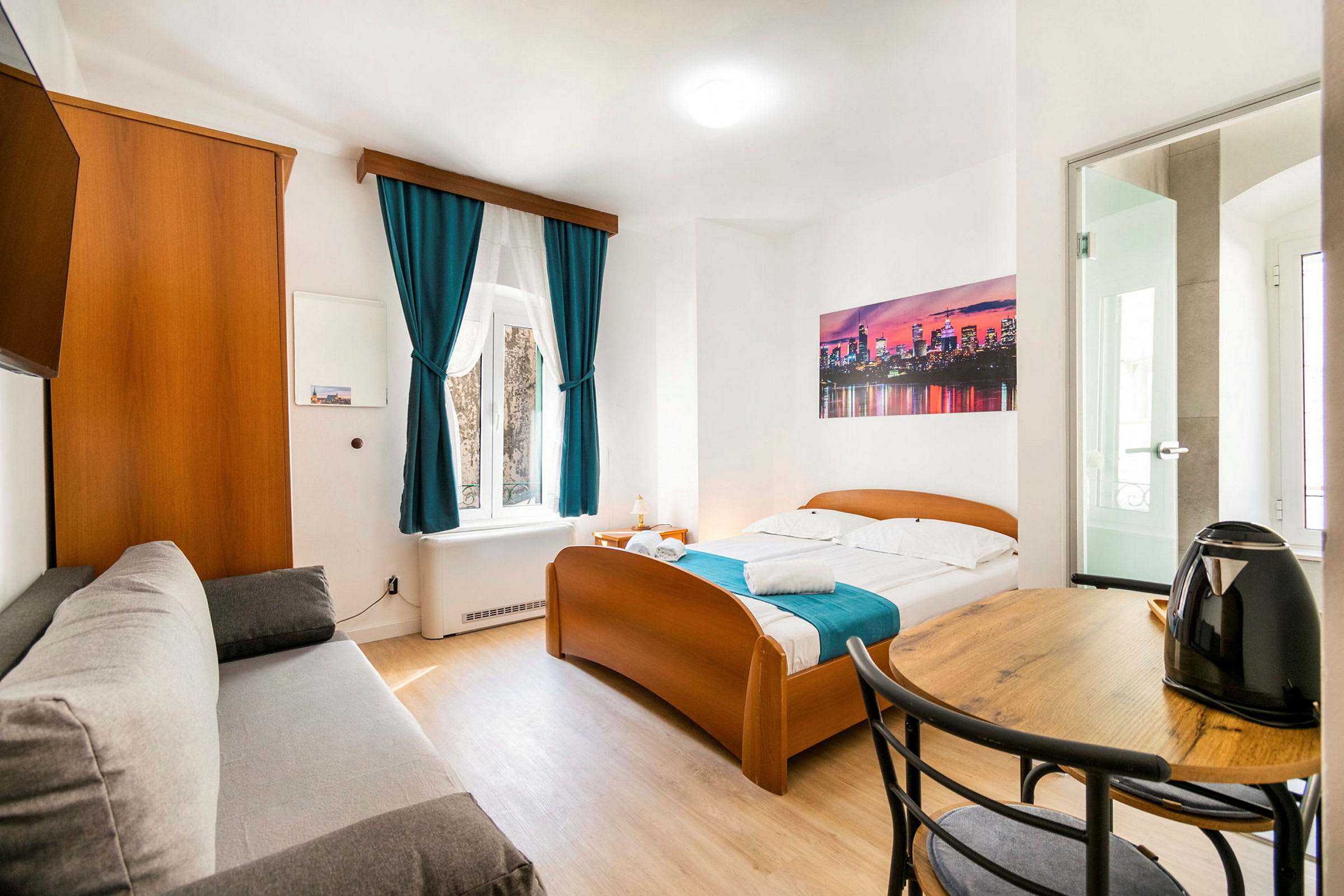 Bild på ett ljust hotellrum med en säng, soffa, bord och en vattenkokare. (AI-genererad text)