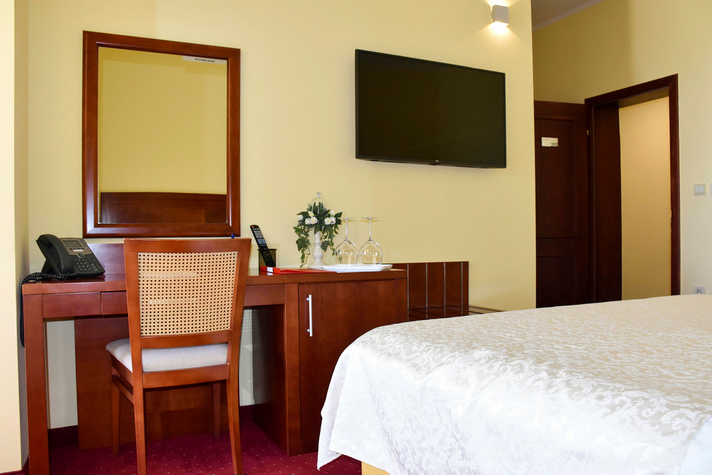 Ett hotellrum med skrivbord, spegel och platt-TV. (AI-genererad text)