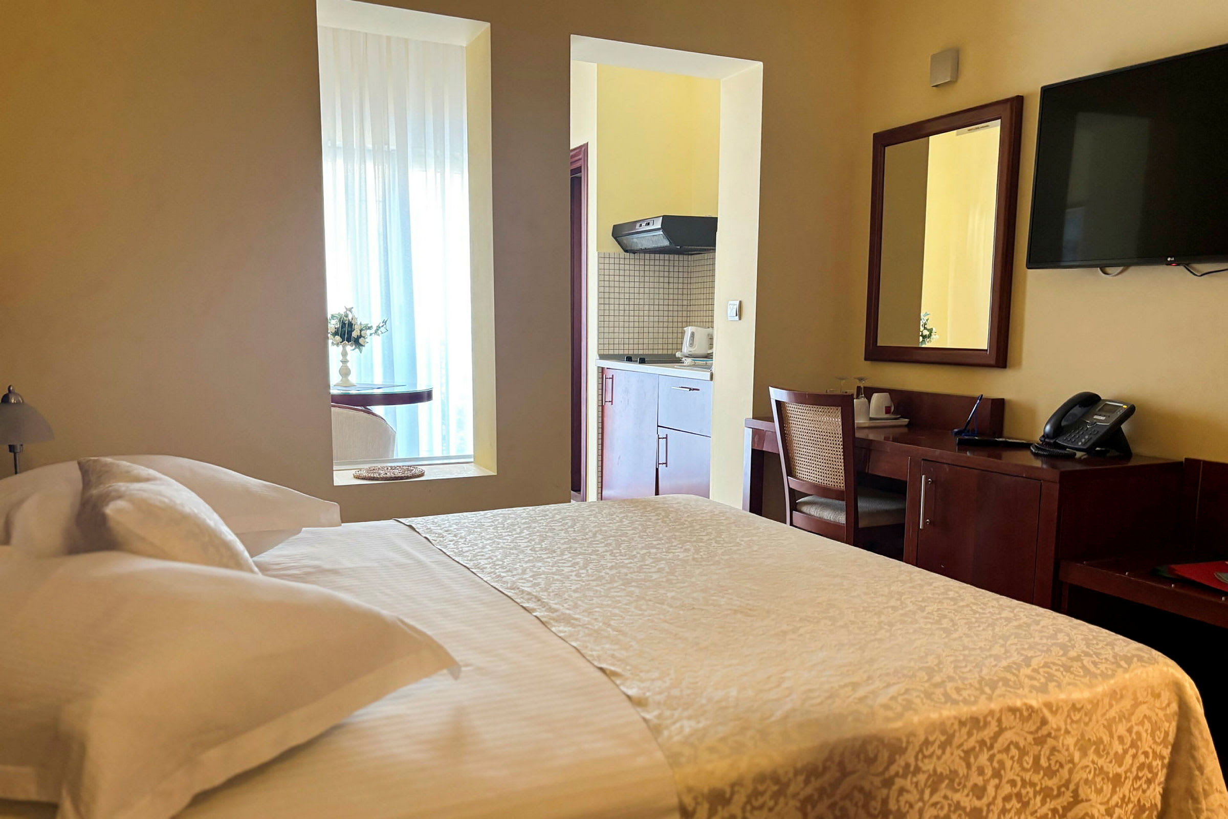 Foto av ett hotellrum med en dubbelsäng, skrivbord och en kökshörna. (AI-genererad text)
