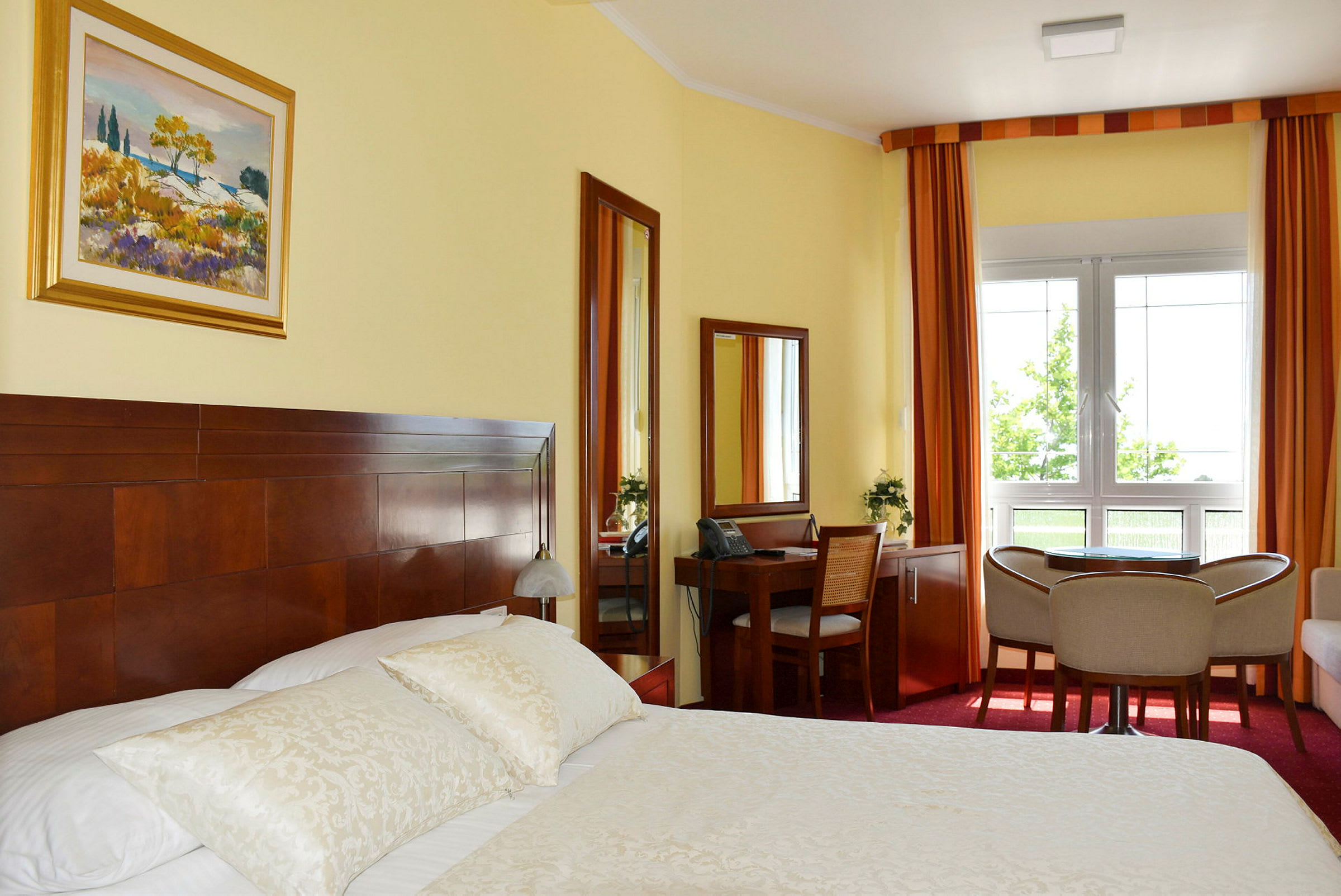 Ett hotellrum med en dubbelsäng, skrivbord, stolar och ett fönster. (AI-genererad text)
