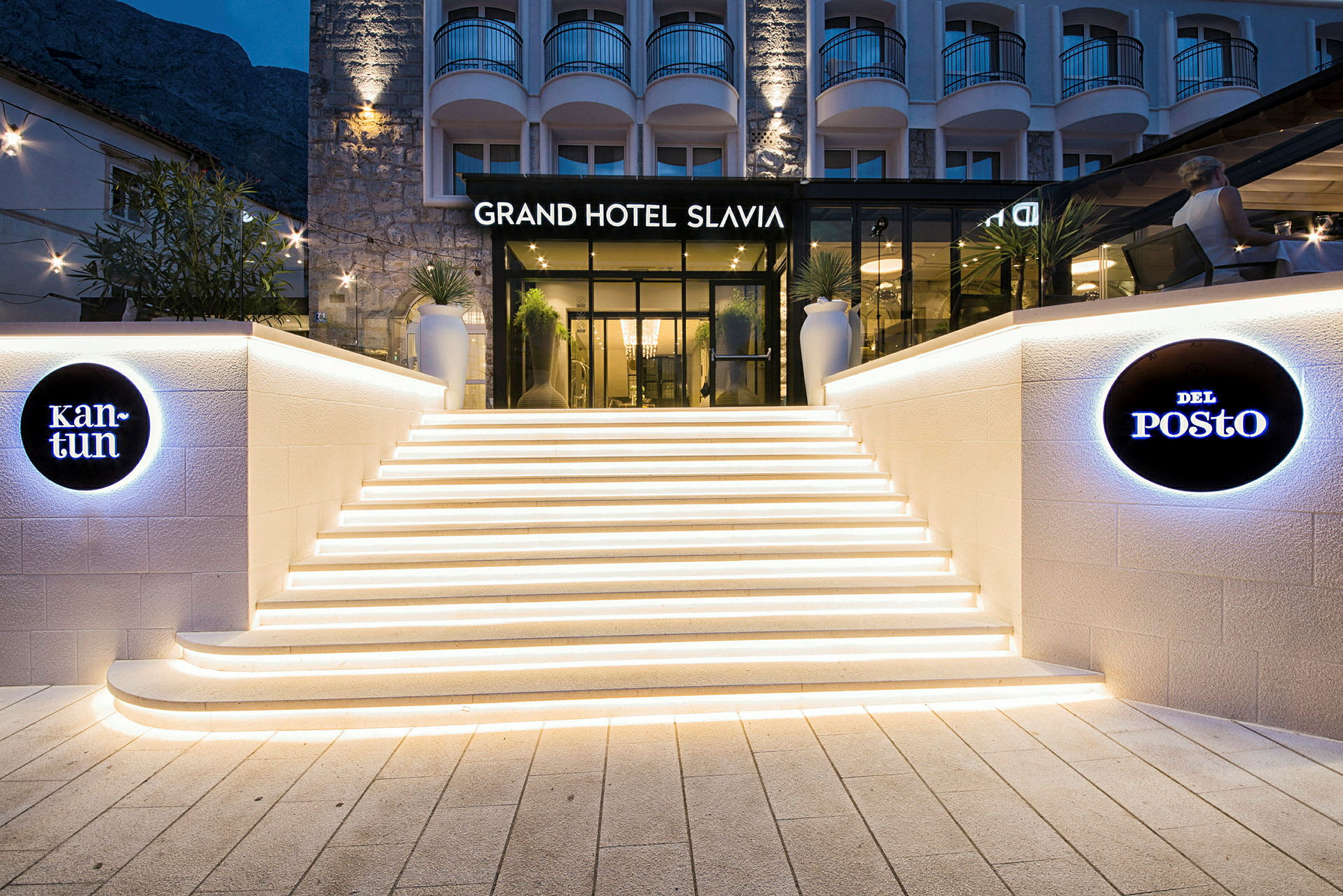 Entré till Grand Hotel Slavia med upplysta trappor och skyltning. (AI-genererad text)