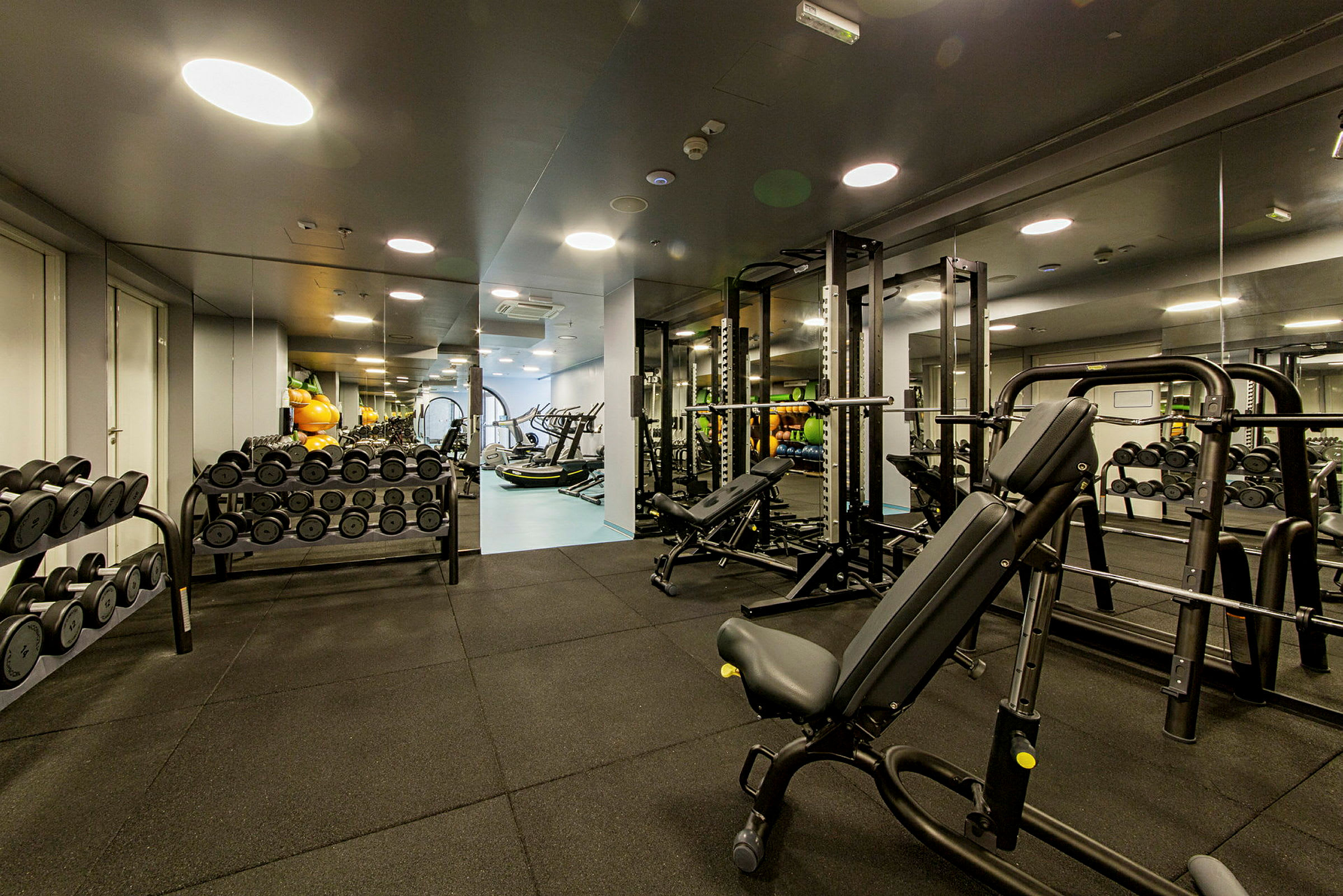Bild av ett gym med träningsutrustning, inklusive viktskivor, hantlar och motionsmaskiner. (AI-genererad text)
