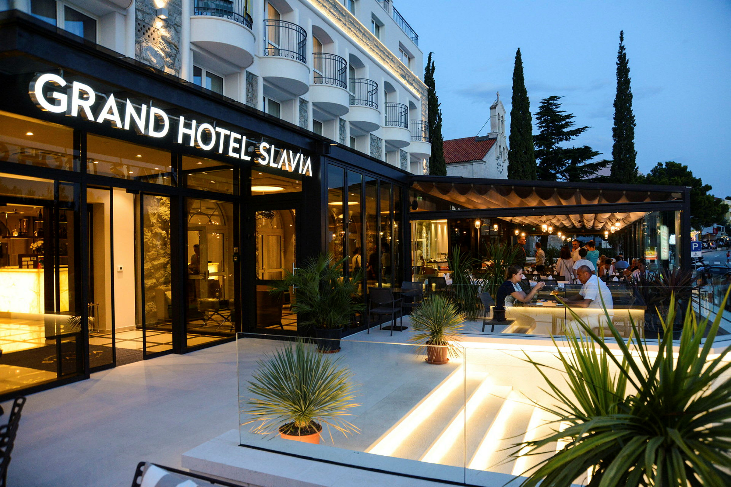 Grand Hotel Slavia med modern uteservering och kvällsbelysning. (AI-genererad text)