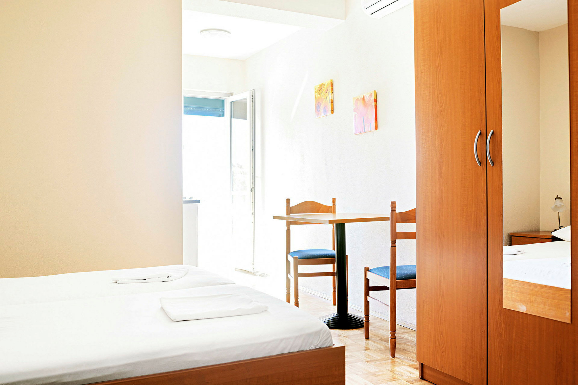 Ett hotellrum med två enkelsängar, ett bord med två stolar och en garderob. (AI-genererad text)