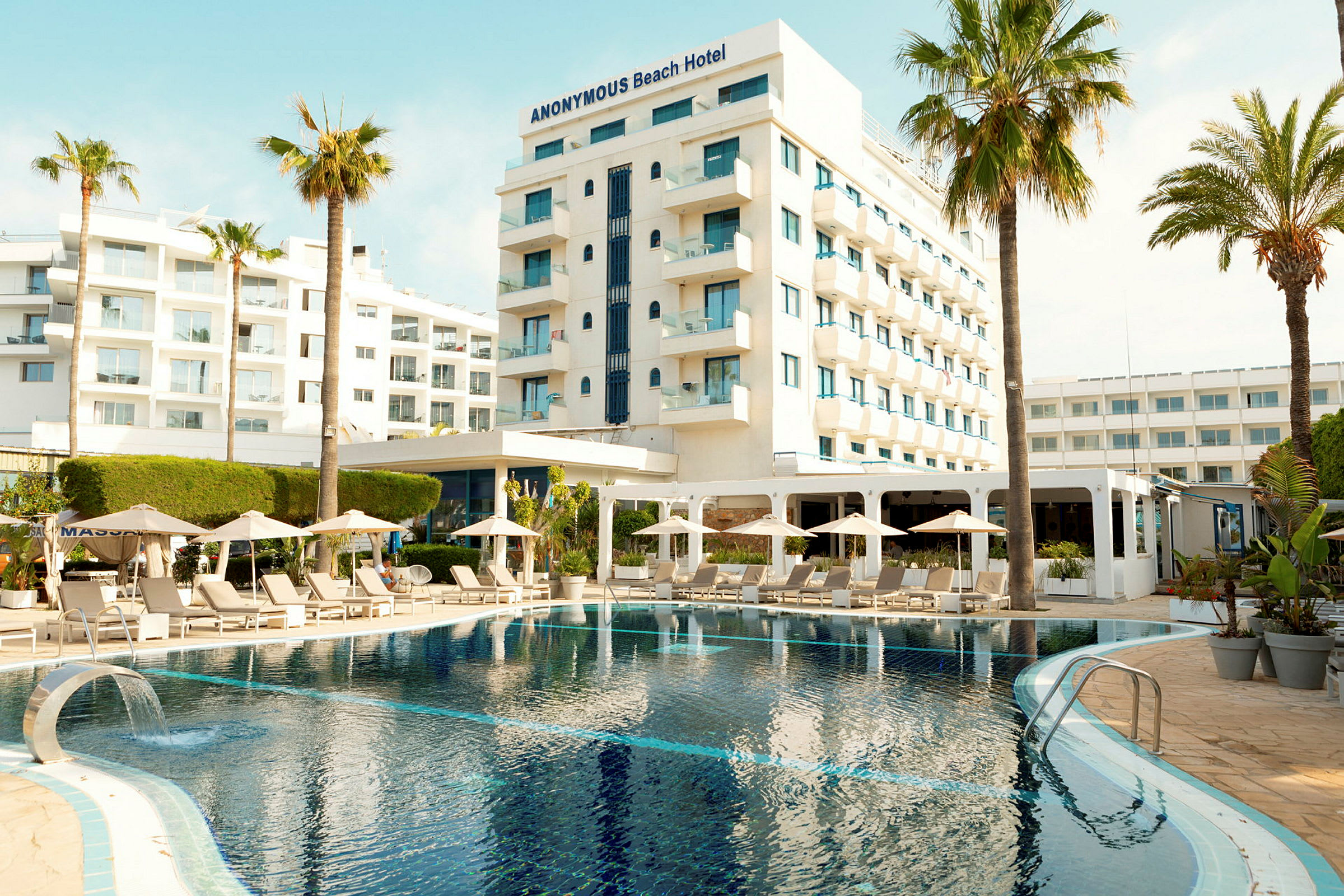 Hotell med pool, solsängar och parasoll i förgrunden. (AI-genererad text)
