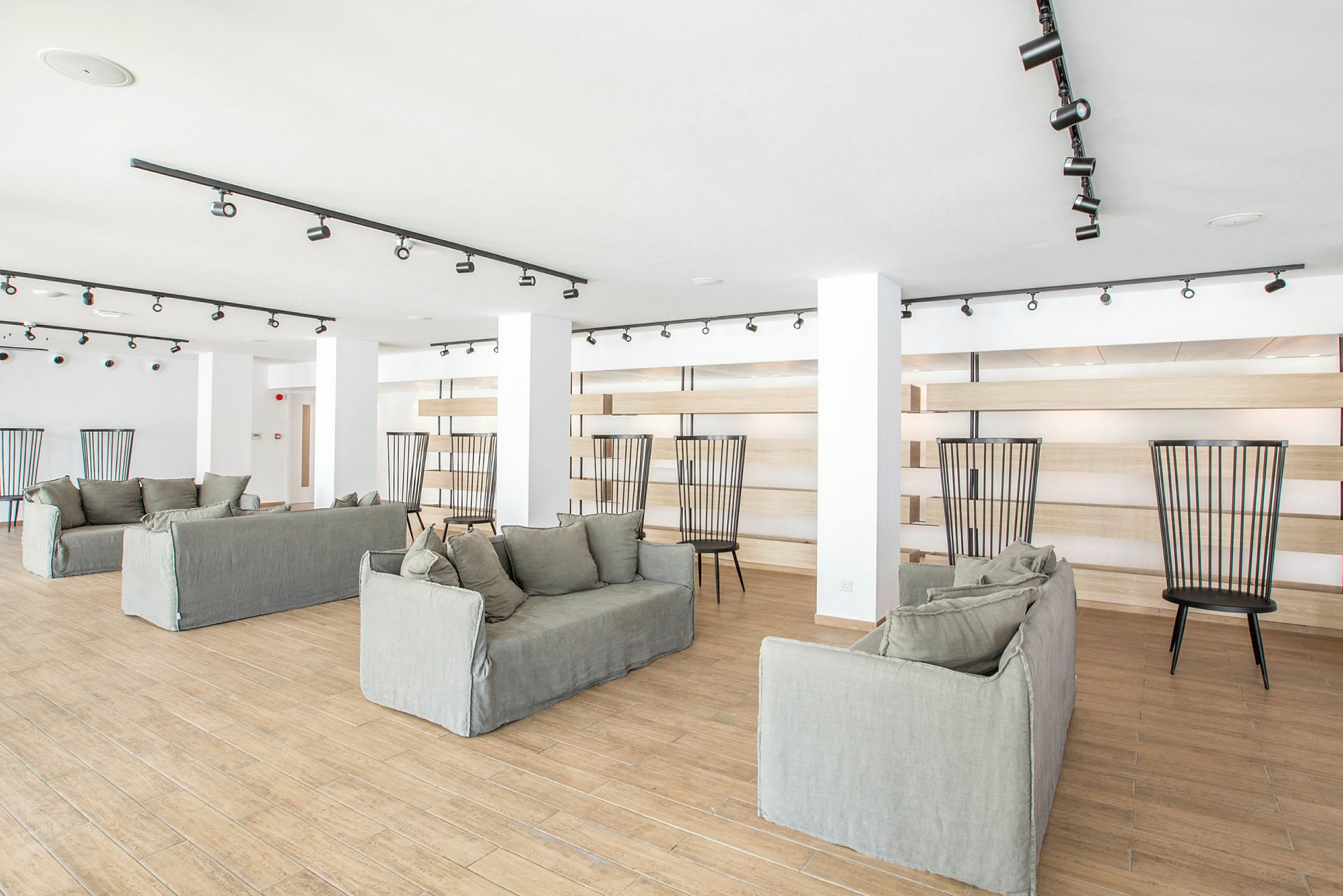 Ett ljust rum med flera soffor och stolar, golvet är gjort av trä och rummet är inrett med modern design. (AI-genererad text)