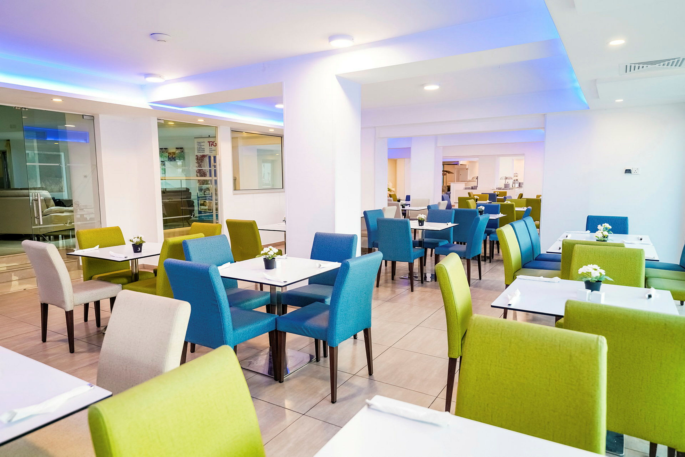 En restaurang med bord och stolar i grön och blå färg. (AI-genererad text)