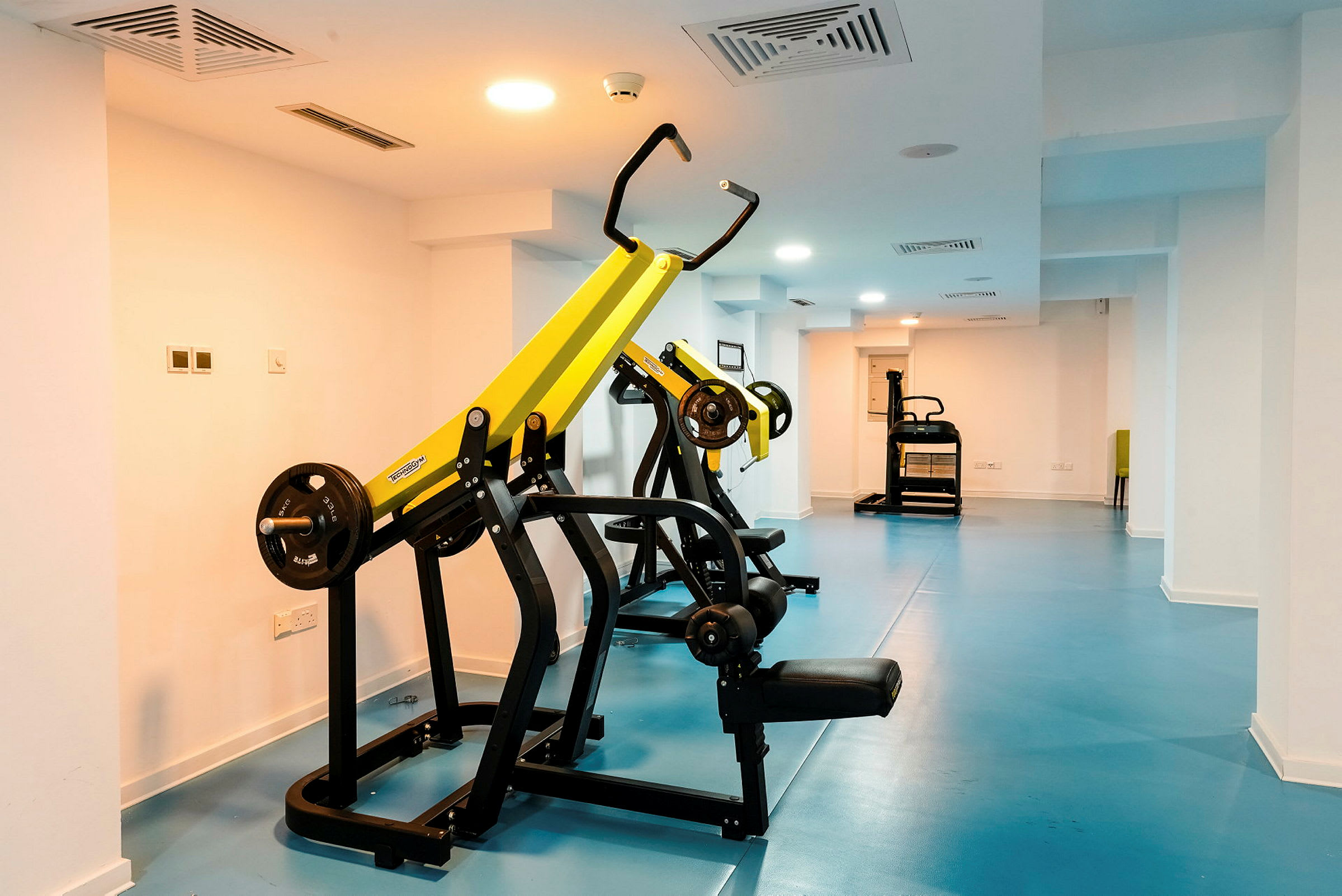 Ett gym med träningsmaskiner och blått golv. (AI-genererad text)
