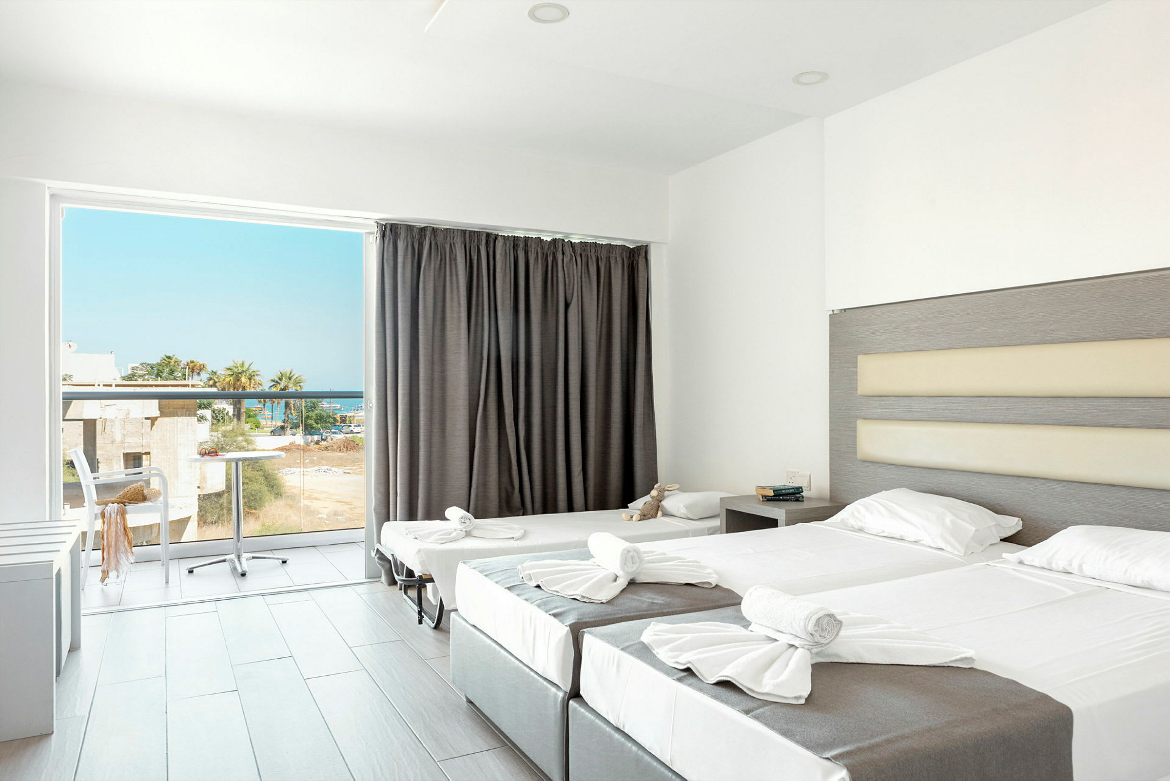 Ett hotellrum med två uppsatta sängar och en balkong med utsikt. (AI-genererad text)