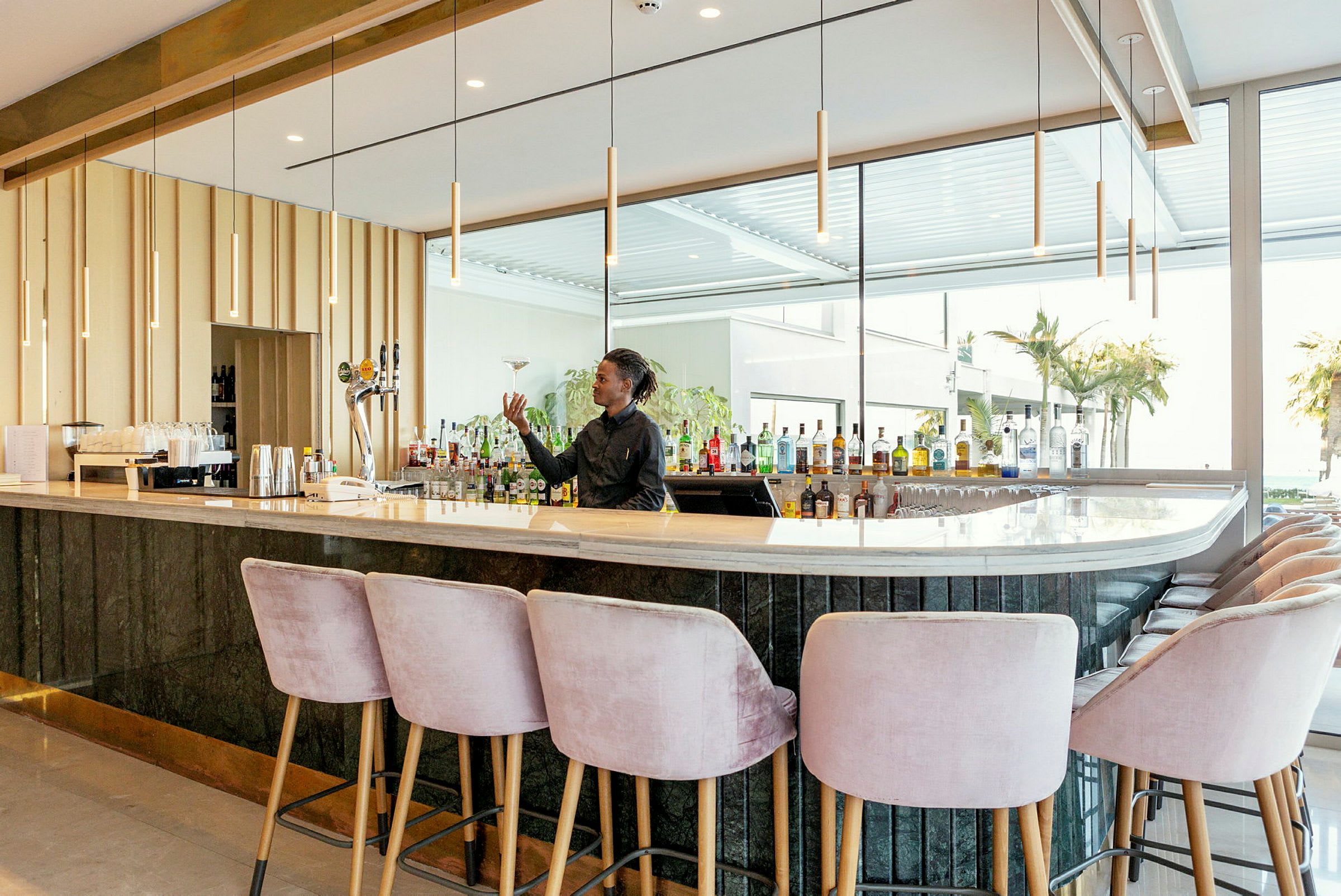 En stilren bar med ljusa stolar och en välfylld bakre bardisk. (AI-genererad text)