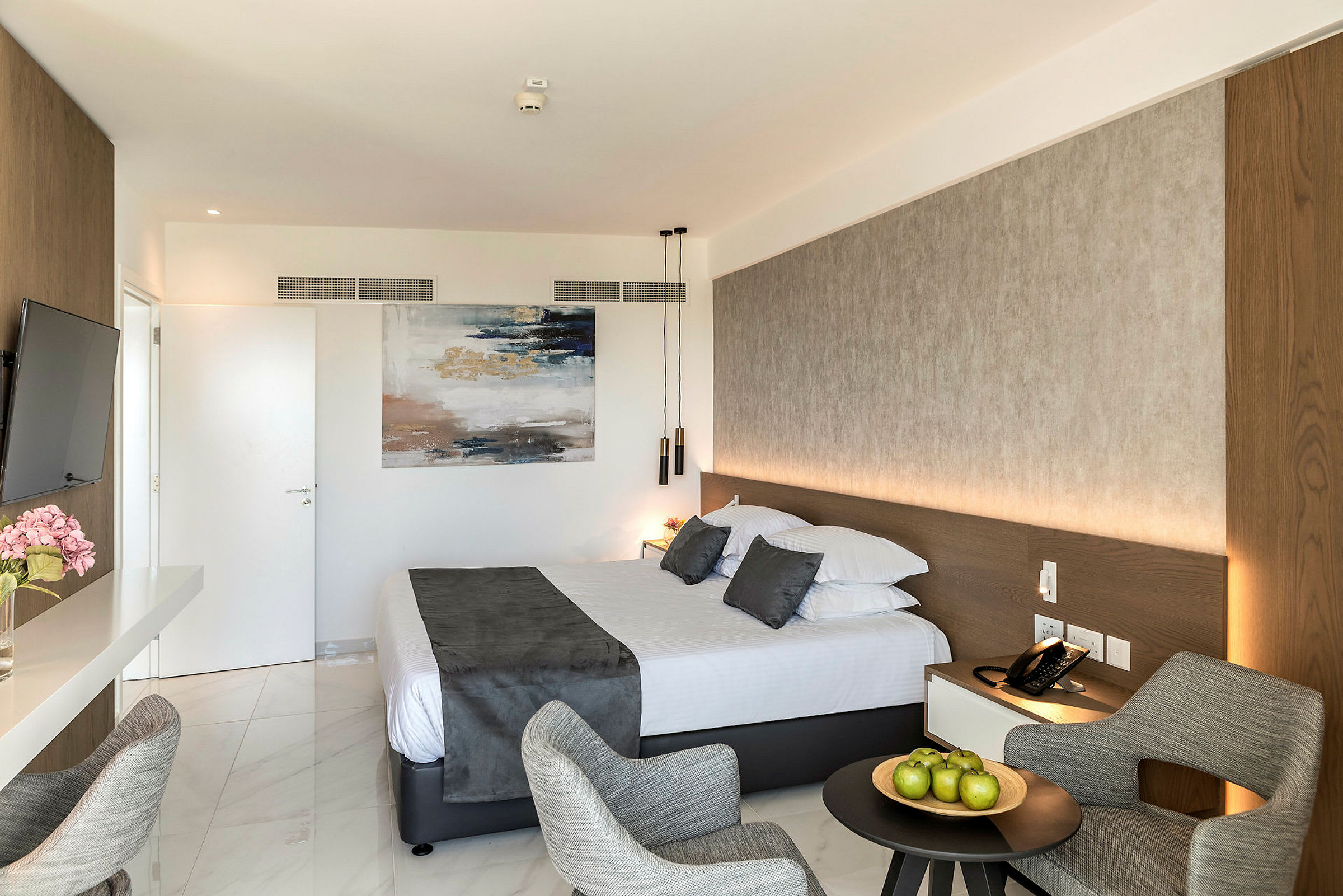 Hotellrum med en dubbelsäng, en sittgrupp och konst på väggen. (AI-genererad text)
